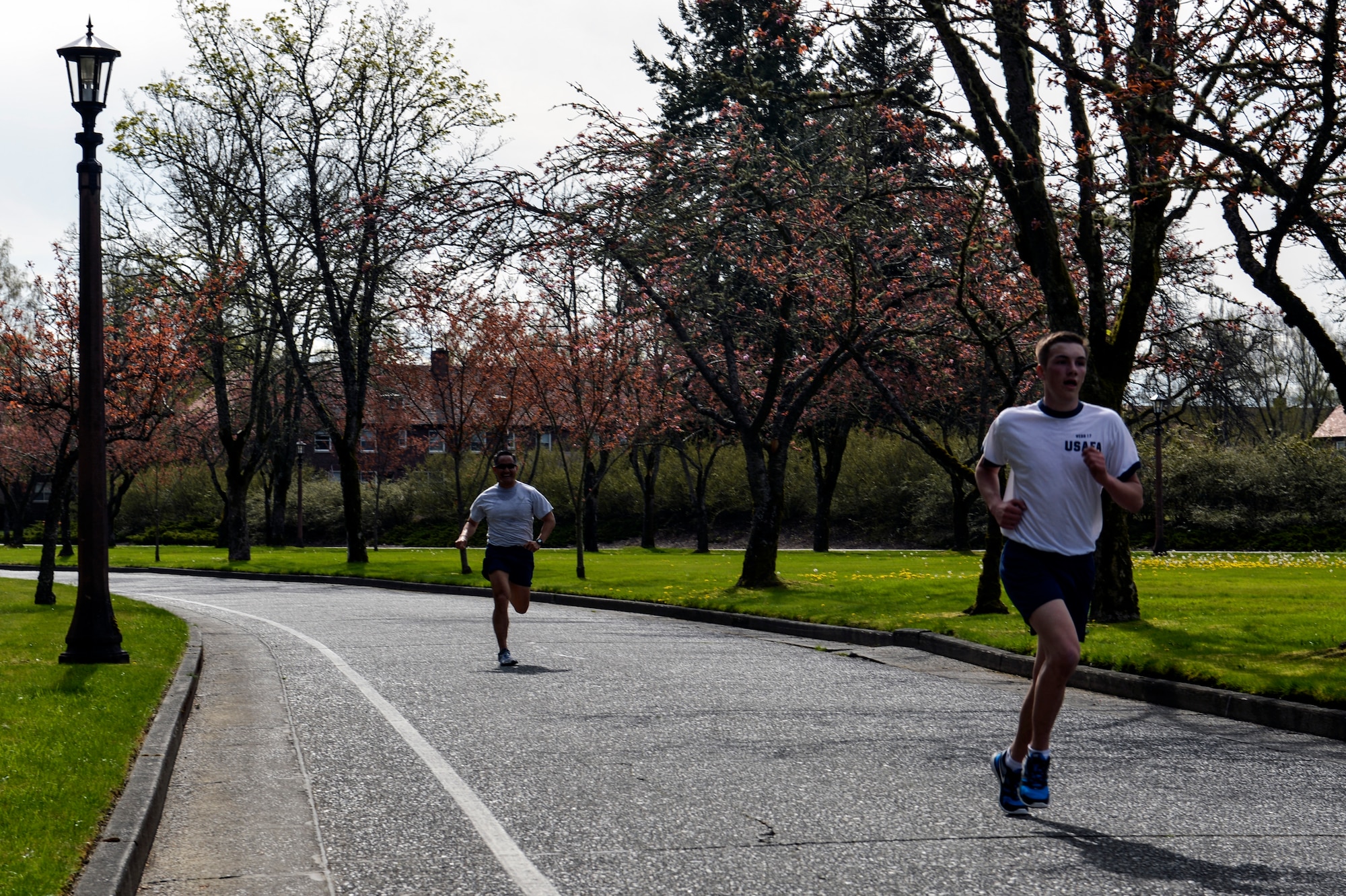Col. David Kumashiro, 62nd Airlift Wing commander, finishes the Team McChord run behind Cadet David Webb, U.S. Air Force Academy student, April 11, 2014 at Joint Base Lewis-McChord, Wash. Kumashiro challenged the USAFA cadets to a race and was only bested by two cadets finishing the 2.02 mile run in under 13 minutes. (U.S. Air Force photo/Staff Sgt. Russ Jackson) 