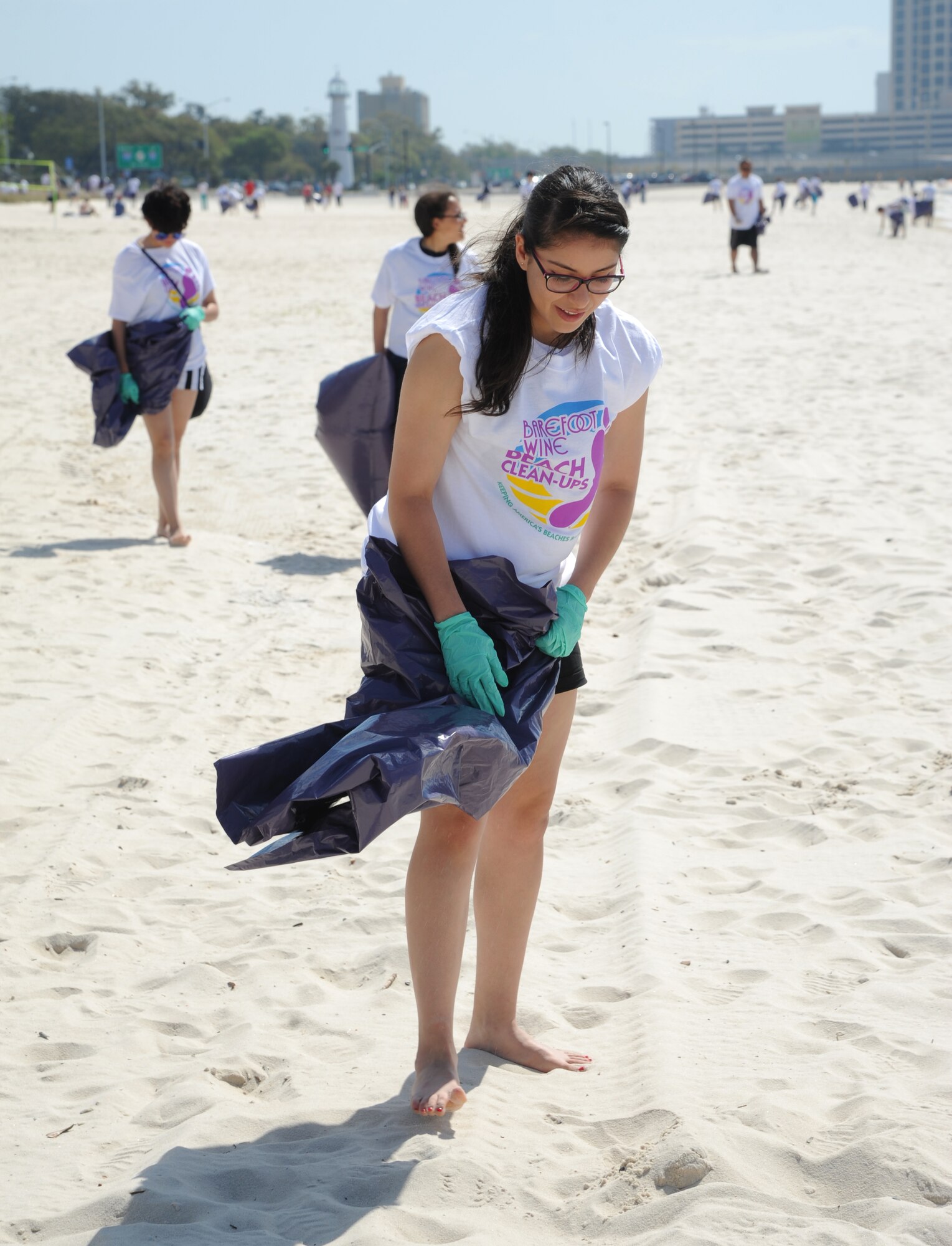 Airman 1st Class Viviana Gutierrez, 335th Training Squadron, along with other Keesler Air Force Base volunteers, survey the sand for trash on the beach during a beach rescue project April 12, 2014, along Highway 90 between White Avenue and Porter Avenue, Biloxi, Miss.  Volunteers were provided with T-shirts, trash bags and gloves.  (U.S. Air Force photo by Kemberly Groue)
