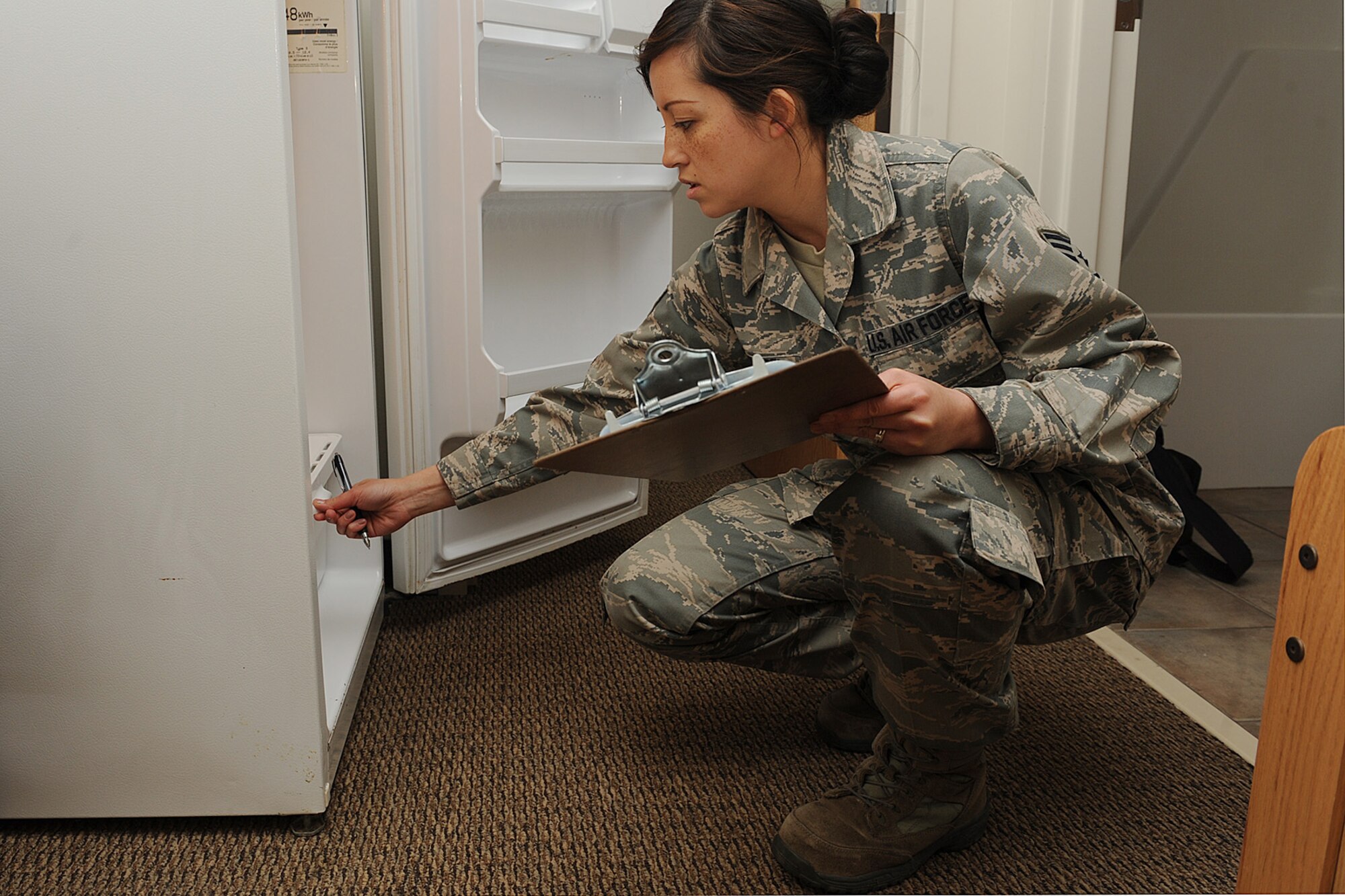 Staff Sgt. Erika Wenzel inspects a refrigerator during a room inspection at Scott Air Force Base, Ill., March 31, 2014. As part of the dormitory management team, she inspects the cleanliness of the rooms in the Belleville, Shiloh and Mascoutah dorms.  She is responsible for mentoring and counseling more than 380 Airmen.  Wenzel is a 375th Civil Engineering Squadron Airman dormitory leader.  (U.S. Air Force photo by Staff Sgt. Maria Bowman)
