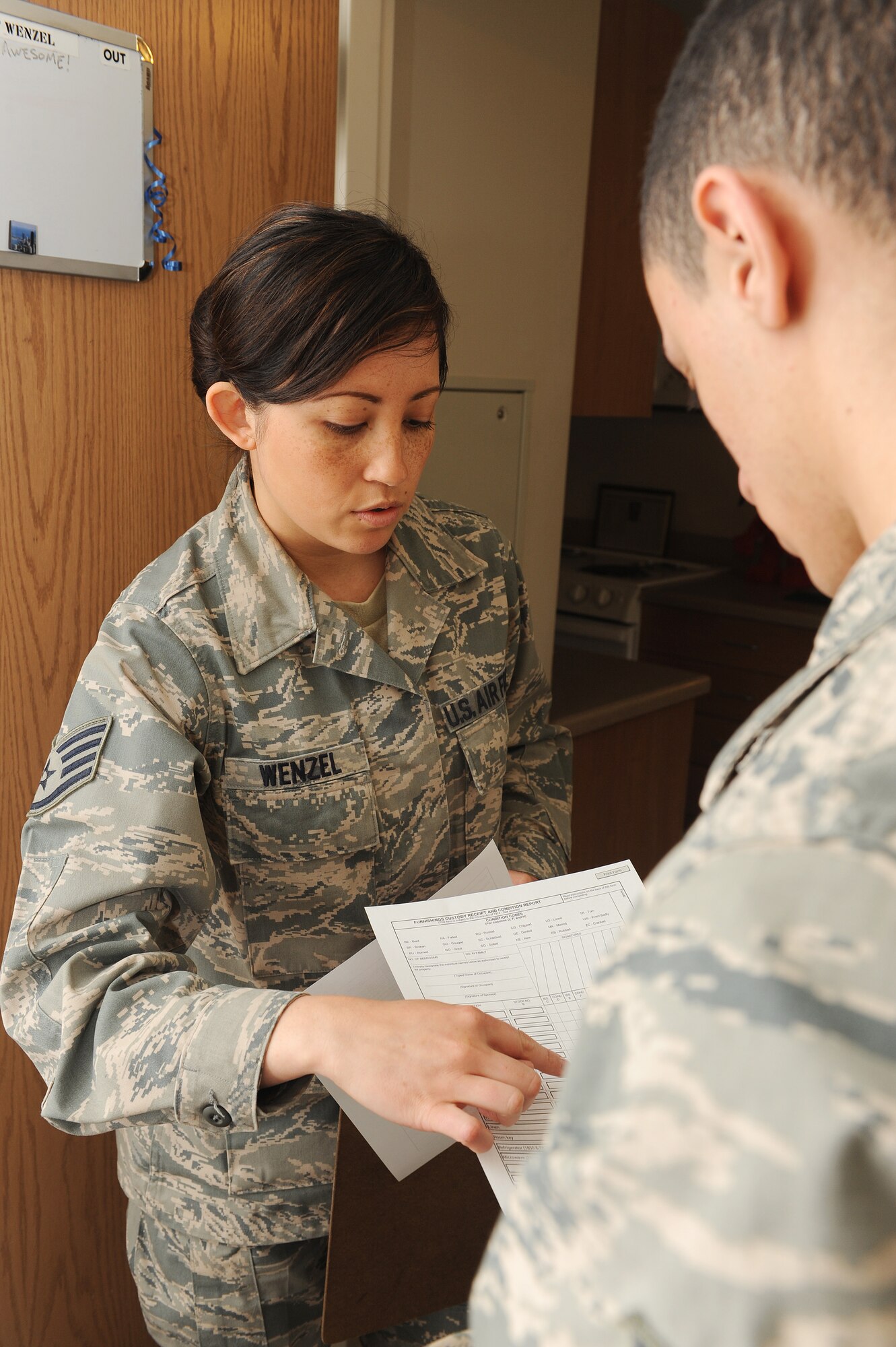Staff Sgt. Erika Wenzel talks to an Airman about the checklist that must be completed prior to changing rooms at Scott Air Force Base, Ill., March 31, 2014.  As part of the dormitory management team, she is responsible for maintaining the dorm facilities, assisting Airmen with problems they are having with their living situation and providing advice.  Wenzel is a 375th Civil Engineering Squadron Airman dormitory leader.  (U.S. Air Force photo by Staff Sgt. Maria Bowman)