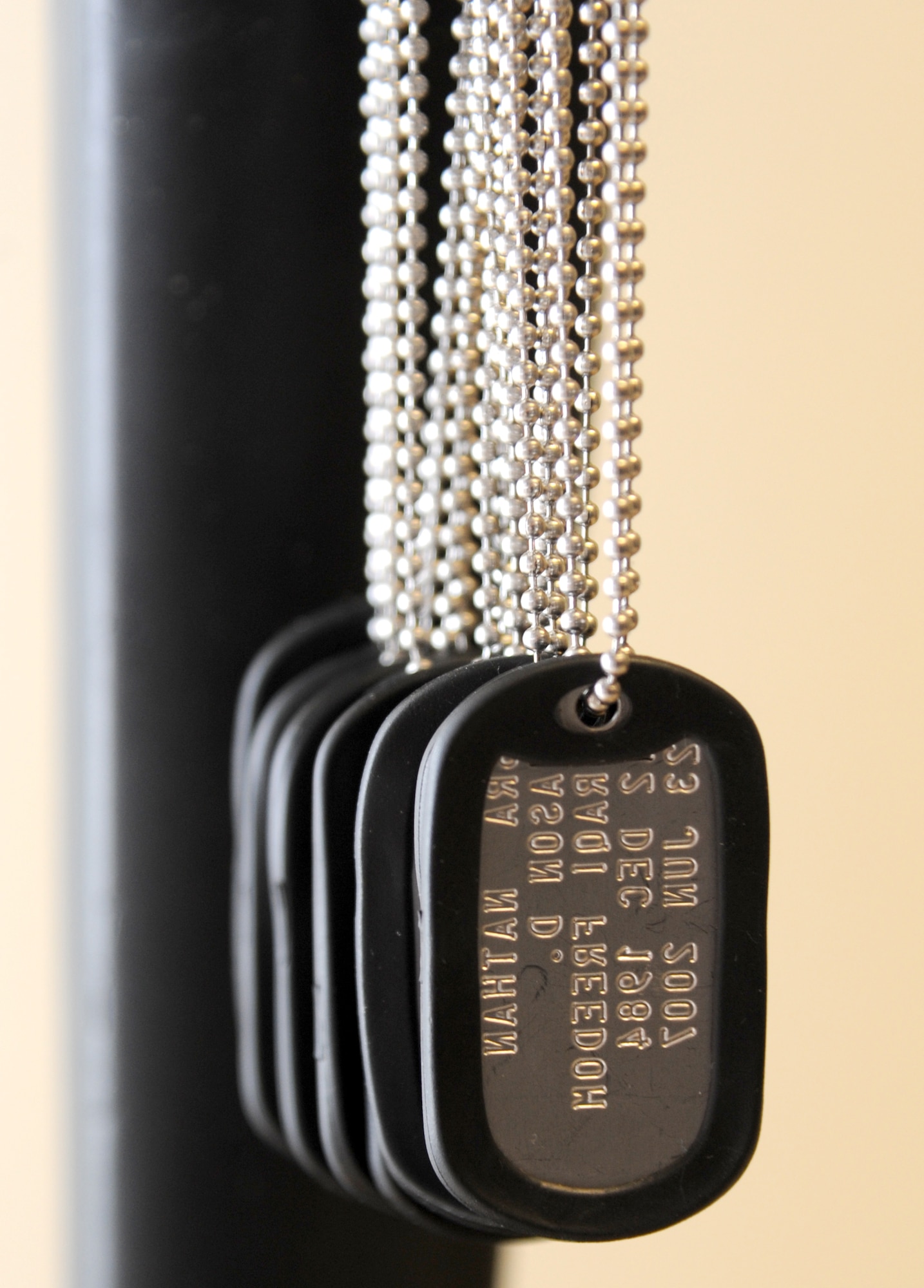 Nine dog tags, one for each of the security forces Airmen who lost their lives during Operation Iraqi Freedom and Operation Enduring Freedom, adorn a “fallen soldier battlefield cross,” which also consists of a standing rifle with a helmet, during a memorial ceremony April 11, 2014, at the 81st Security Forces Squadron building, Keesler Air Force Base, Miss. The ceremony included the unveiling of the memorial and remarks by base leadership and members of the 81st SFS. The biographies of the deceased Airmen are mounted on the wall behind the memorial. (U.S. Air Force photo by Kemberly Groue)