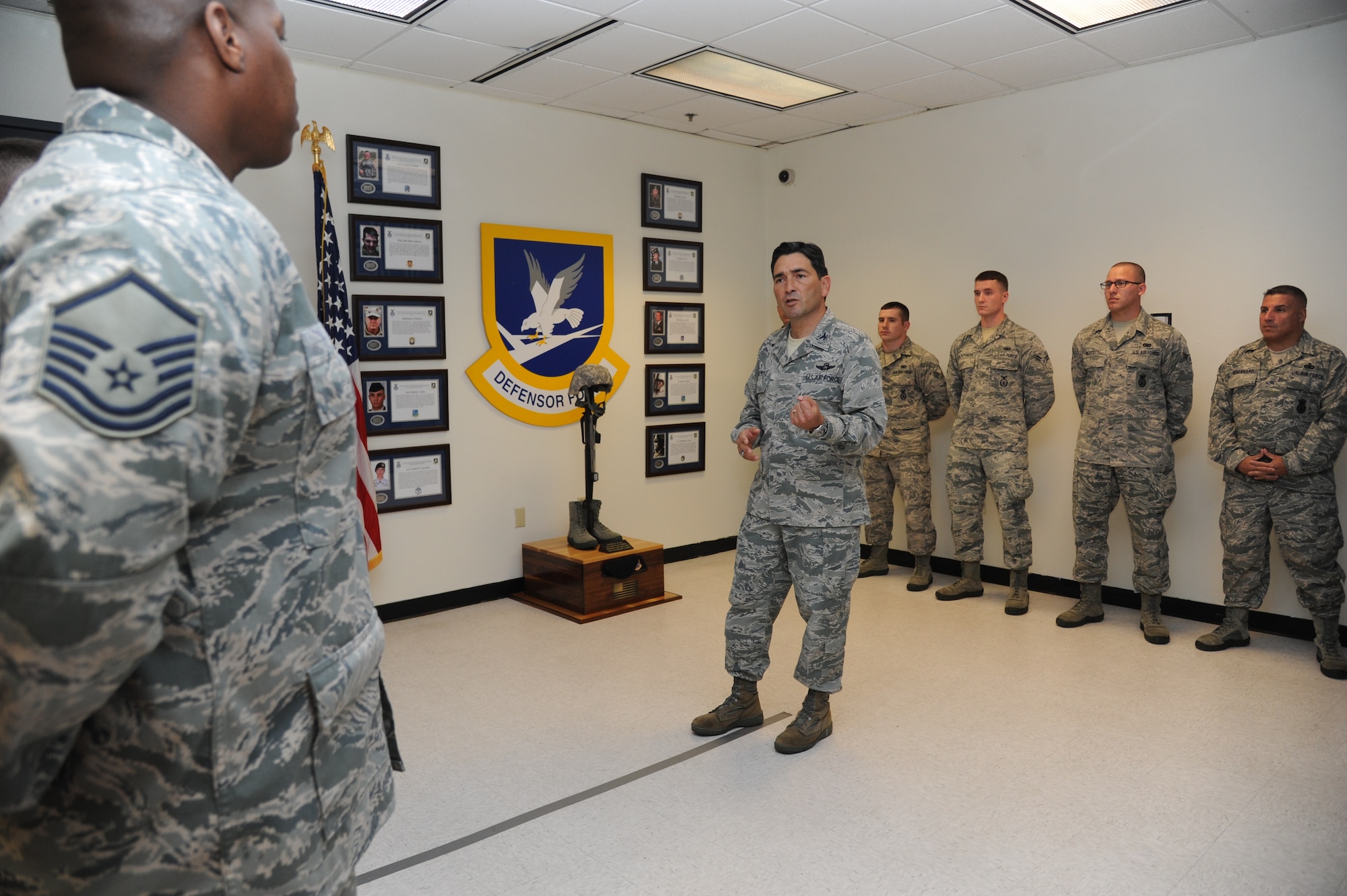 Col. René Romero, 81st Training Wing vice commander, makes remarks during a memorial ceremony honoring the nine security forces Airmen who lost their lives during Operation Iraqi Freedom and Operation Enduring Freedom April 11, 2014, at the 81st Security Forces Squadron building, Keesler Air Force Base, Miss.  The ceremony included the unveiling of a “fallen soldier battlefield cross,” which consists of a standing rifle with a helmet and dog tags adorning it, and boots at the base. The biographies of the deceased Airmen are mounted on the wall behind the memorial. (U.S. Air Force photo by Kemberly Groue)