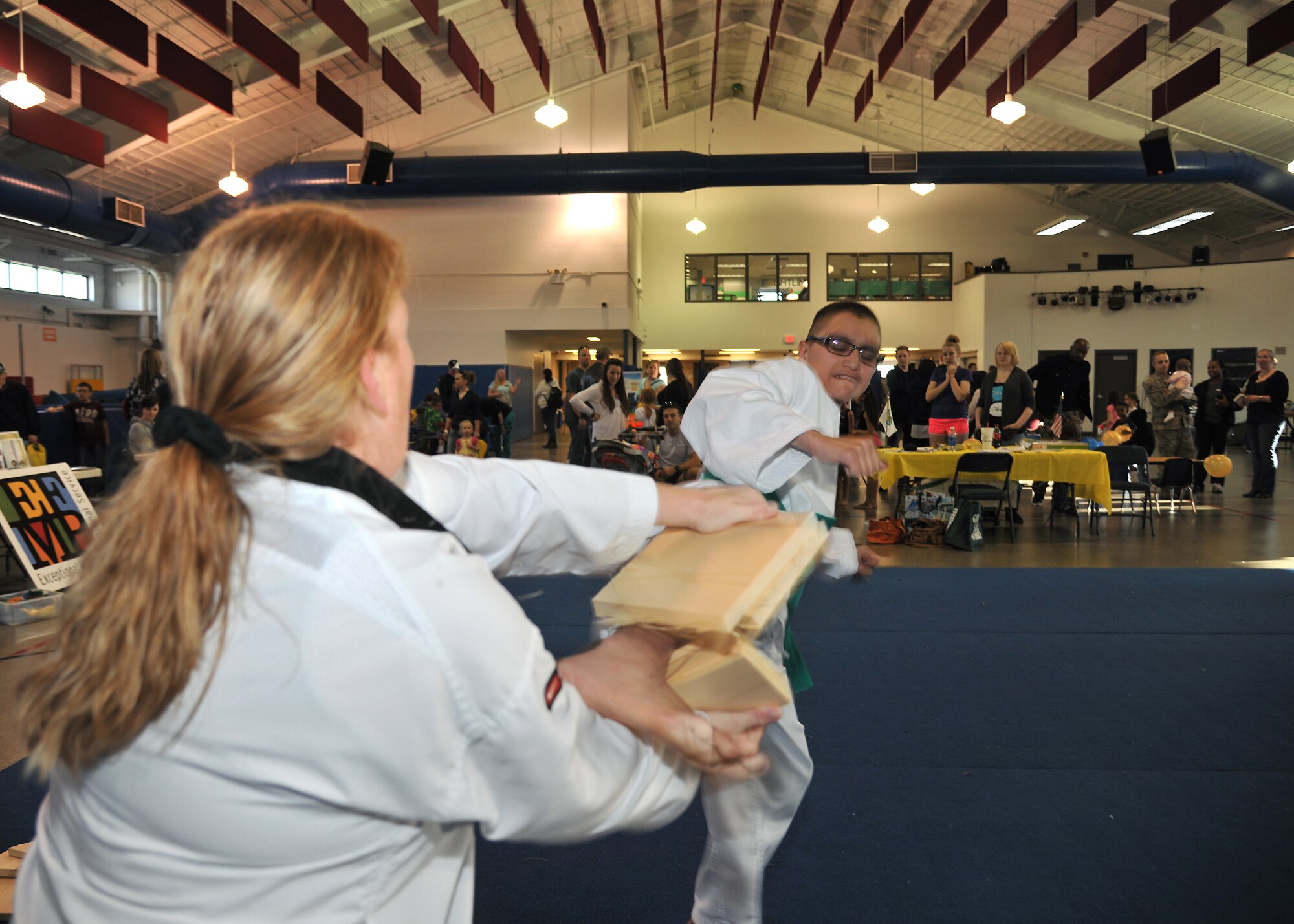 Isaiah Lopez, 12, kicks through two wooden boards held by Red River Tae Kwan Do instructor Missy Thacher, April 9, 2014, at Liberty Square on Grand Forks AFB, N.D. Martial arts demonstrations for parents and children were a feature of the Beautiful Child Photo Shoot and Activity Fair. (U.S. Air Force photo/Senior Airman Xavier Navarro)