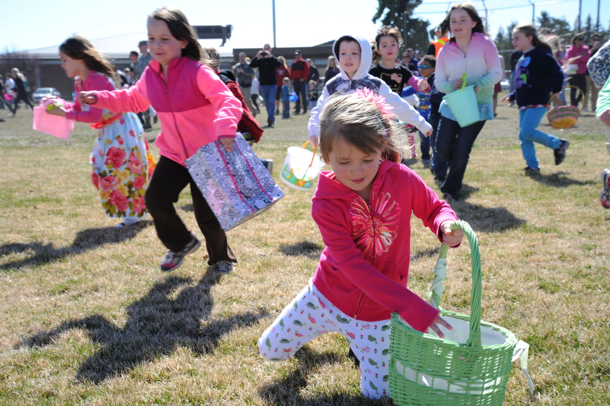 Children rush forward gathering candy-filled Easter eggs during an Easter egg hunt event at Fairchild Air Force Base, Wash., April 12, 2014. The event was sponsored by the 92nd Force Support Squadron. (U.S. Air Force photo by Airman 1st Class Janelle Patiño/Released)