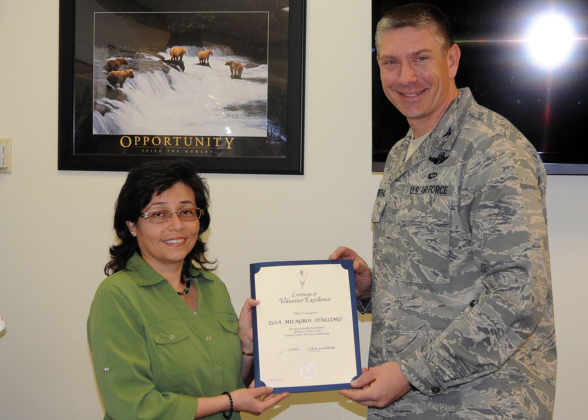 ALTUS AIR FORCE BASE, Okla. – U.S. Air Force Col. Bill Spangenthal, 97th Air Mobility Wing commander, awards Mili Stallings, 97th Medical Operations Squadron executive assistant, with the 2013 Altus AFB Volunteer Excellence award certificate at the Airman and Family Readiness Center April 11, 2014. The award was established to recognize individuals who performed outstanding volunteer service that impacts a military installation or surrounding community. (U.S. Air Force photo by Senior Airman Levin Boland/Released)