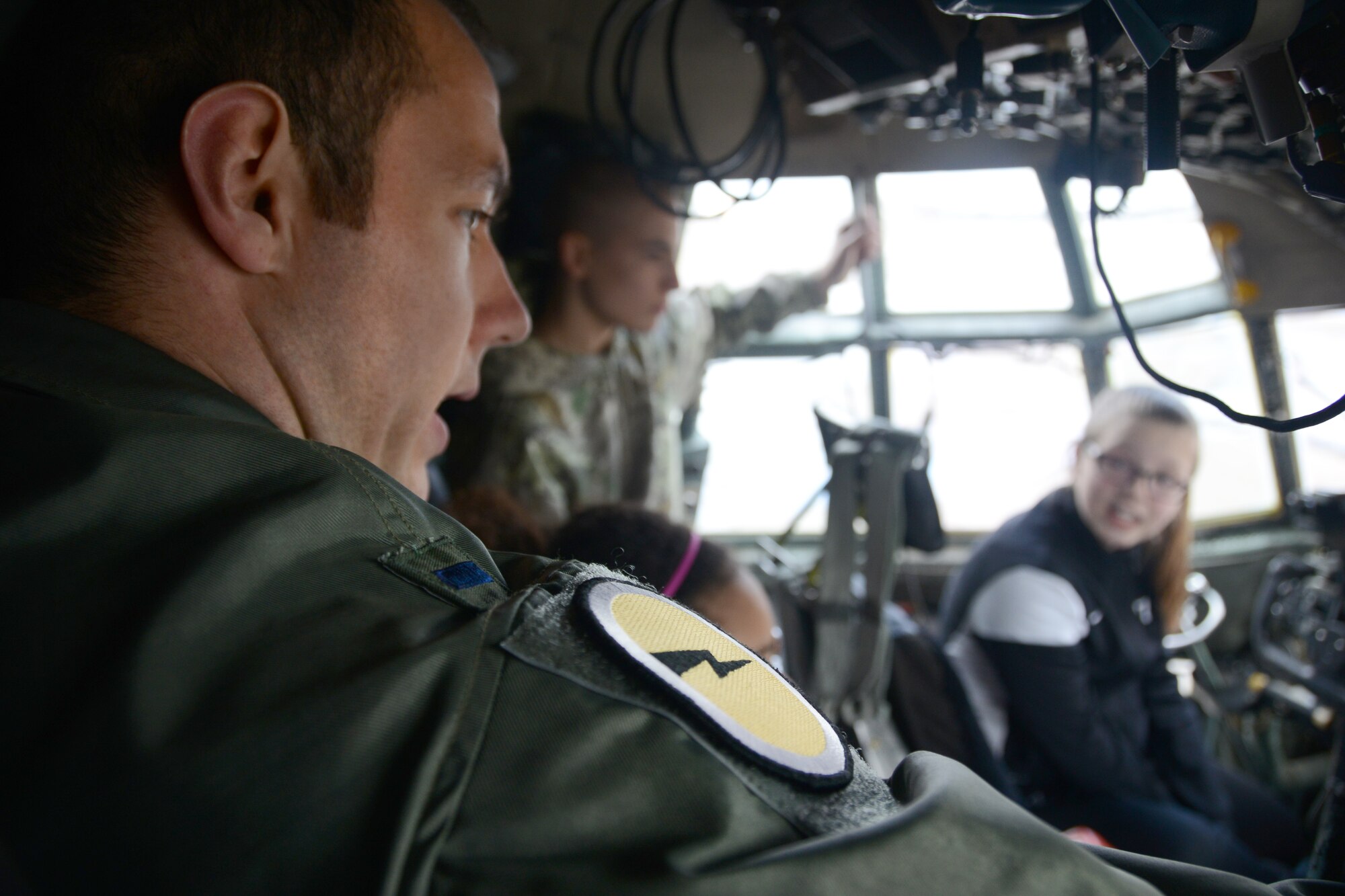 1st Lt. Paul Bolduc, C-130H pilot with the 118th Airlift Squadron, points out and explains the small emergency exit window, among other things, located in the cockpit of a C-130H to a group of Connecticut Air Guard youth at Bradley Air National Guard Base, East Granby, on April 5, 2014. In the background two of the youth participants, Cody Kirkland, 16, and Tori Pilletere, 12, ask questions and get a feel for what it’s like to be a pilot as a Flying Yankee. (U.S. Air National Guard photo by Tech. Sgt. Joshua Mead)