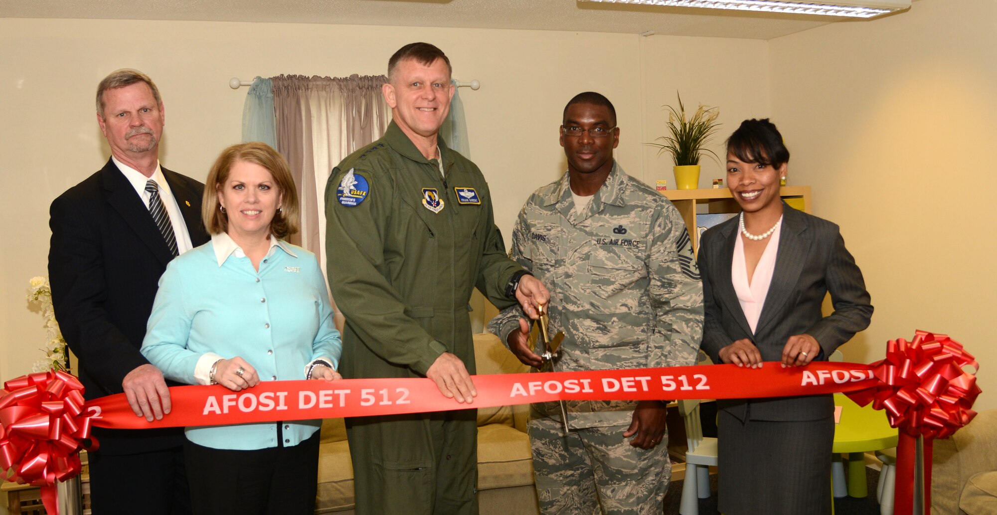 U.S. Air Force Gen. Frank Gorenc, U.S. Air Forces in Europe and Air Forces Africa commander, center, cuts the ribbon on a new interview room for the Air Force Office of Special Investigations Detachment 512 April 14, 2014, on RAF Mildenhall, England. Gorenc visited RAF Mildenhall and RAF Alconbury during his tour of the U.K. The primary purpose for the room is for AFOSI agents to meet with and interview victims of sexual assault in a non-threatening space. (U.S. Air Force photo by Airman 1st Class Kelsey Waters/Released)
