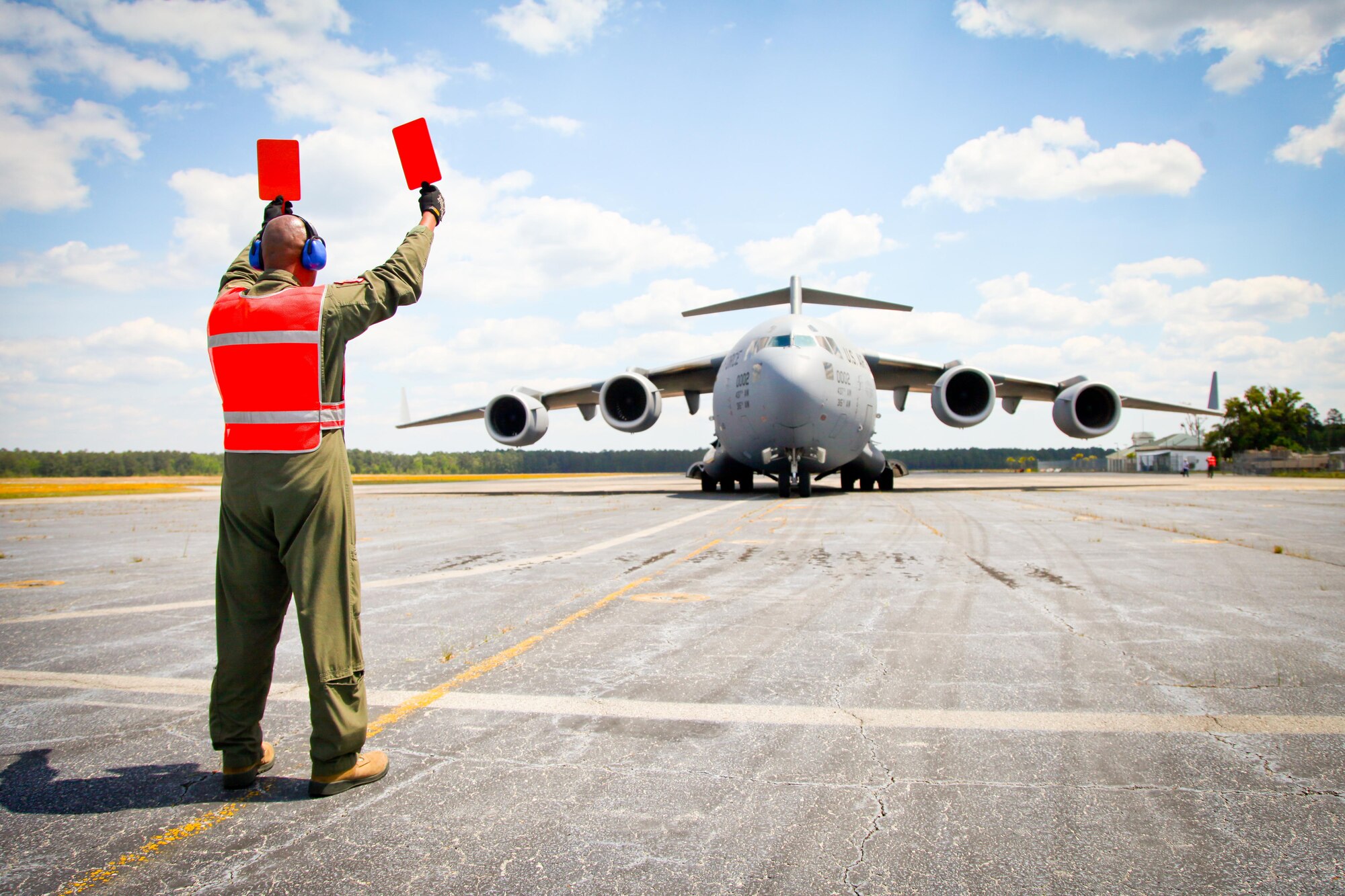 Master Sgt. Eric Walker, a loadmaster with the 315th Airlift Control Flight at Joint Base Charleston, S.C., marshals in a C-17 Globemaster III to its parking spot Friday at Wright Army Airfield, Ga. C-17's from JB Charleston, S.C., and Wright-Patterson Air Force Base, Ohio, transported four tanks from Wright AAF to McEntire Air National Guard Base, S.C., in support of a tank movement for the 1/118th CAB. (U.S. Air Force photo by Staff Sgt. Rashard Coaxum/released)