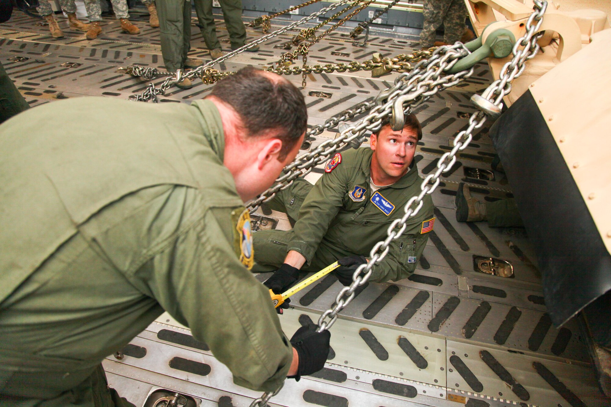 Tech Sgt. Vinnie White, a loadmaster with the 315th Airlift Control Flight, pulls measuring tape to measure the length of tie down chains onboard a C-17 Globemaster III Thursday at Wright Army Airfield, Ga. C-17's from JB Charleston, S.C., and Wright-Patterson Air Force Base, Ohio, transported four tanks from Wright AAF to McEntire Air National Guard Base, S.C., in support of a tank movement for the 1/118th CAB. (U.S. Air Force photo by Staff Sgt. Rashard Coaxum/released)
