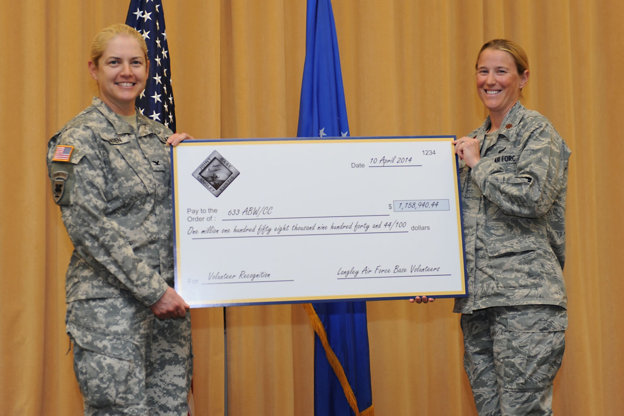U.S. Air Force Maj. Carrie Wentzel, acting 633rd Force Support Squadron commander, presents a check to U.S. Army Col. Jayne Jansen, 633rd Air Base Wing vice commander, during the Joint Base Langley- Eustis Volunteer Salute at Langley Air Force Base, Va., April 10, 2014. Volunteers saved JBLE more than $1.1 million in 2013. Outstanding Volunteer Certificates and Excellence Awards were also presented during the Volunteer Salute. (U.S. Air Force photo by Senior Airman Brittany Paerschke-O’Brien/Released)