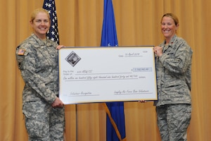 U.S. Air Force Maj. Carrie Wentzel, acting 633rd Force Support Squadron commander, presents a check to U.S. Army Col. Jayne Jansen, 633rd Air Base Wing vice commander, during the Joint Base Langley- Eustis Volunteer Salute at Langley Air Force Base, Va., April 10, 2014. Volunteers saved JBLE more than $1.1 million in 2013. Outstanding Volunteer Certificates and Excellence Awards were also presented during the Volunteer Salute. (U.S. Air Force photo by Senior Airman Brittany Paerschke-O’Brien/Released)