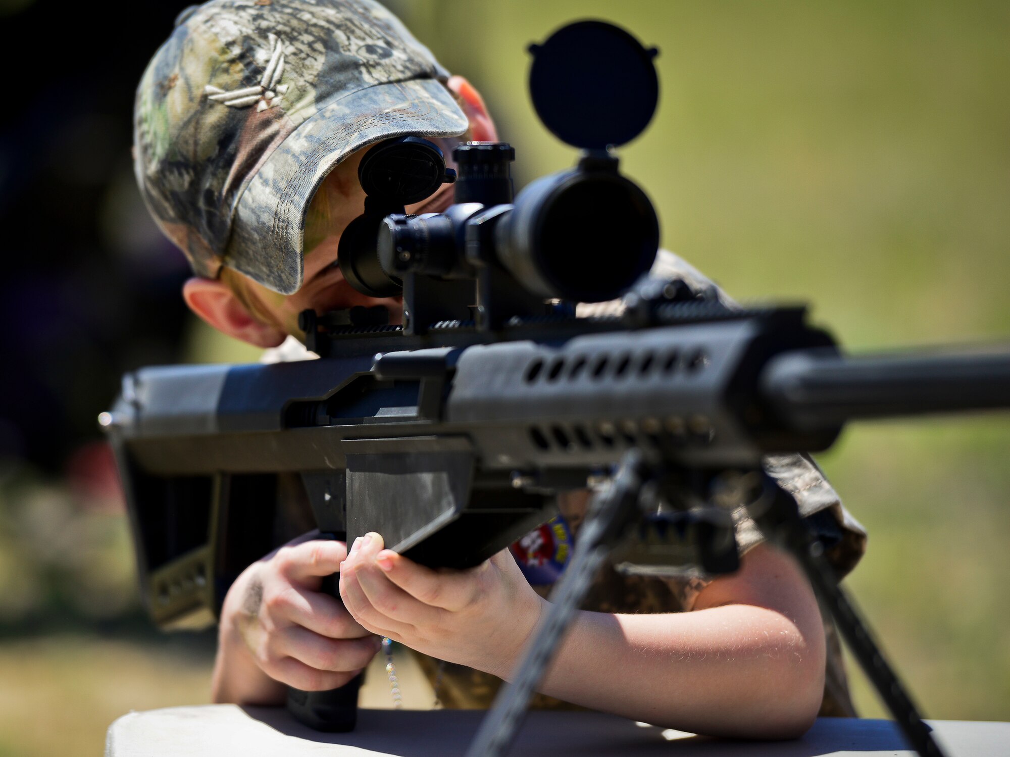 A little deployer looks down the scope of a sniper rifle during Operation Hero April 12 at Eglin Air Force Base, Fla.  Nearly 400 adults and children participated in the program this year, which served as a way to help children understand the military and the deployment process their parents have or could face.  The kids went through a deployment line to get their uniforms, dog tags and shots before they were briefed by their commander and shipped off to a deployed location.  There, they encountered military demonstrations, equipment and obstacle courses.  (U.S. Air Force photo/Samuel King Jr.)