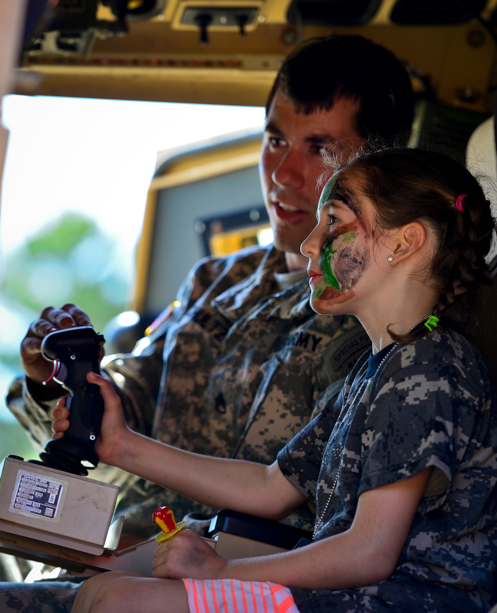 A little deployer gets a lesson on how to move the turret on top of a mine resistant ambush protected  vehicle from a 7th Special Forces Group Soldier during Operation Hero April 12 at Eglin Air Force Base, Fla.  Nearly 400 adults and children participated in the program this year, which served as a way to help children understand the military and the deployment process their parents have or could face.  The kids went through a deployment line to get their uniforms, dog tags and shots before they were briefed by their commander and shipped off to a deployed location.  There, they encountered military demonstrations, equipment and obstacle courses.  (U.S. Air Force photo/Samuel King Jr.)