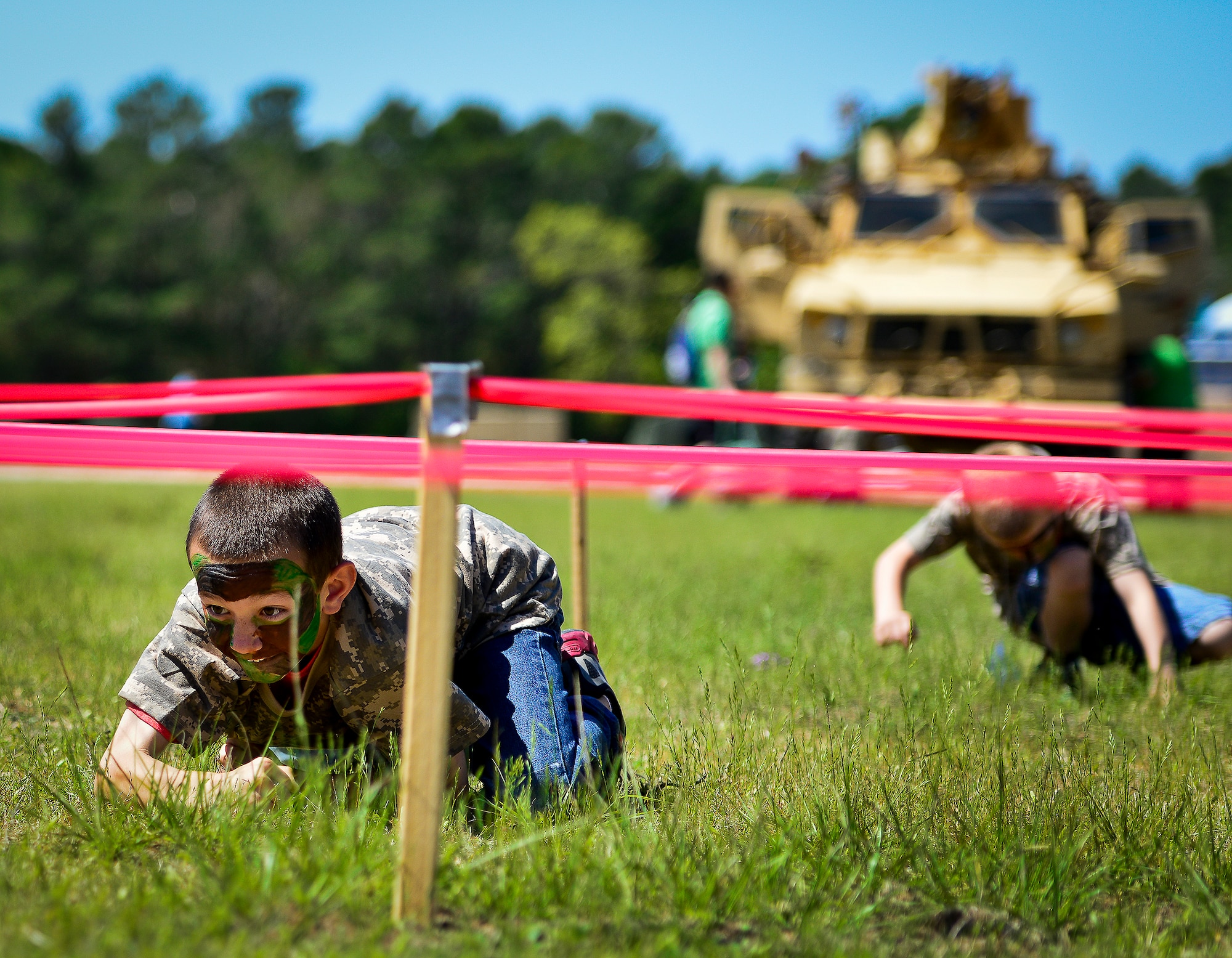A little deployer low-crawls through a maze of red tape during Operation Hero April 12 at Eglin Air Force Base, Fla.  Nearly 400 adults and children participated in the program this year, which served as a way to help children understand the military and the deployment process their parents have or could face.  The kids went through a deployment line to get their uniforms, dog tags and shots before they were briefed by their commander and shipped off to a deployed location.  There, they encountered military demonstrations, equipment and obstacle courses.  (U.S. Air Force photo/Samuel King Jr.)