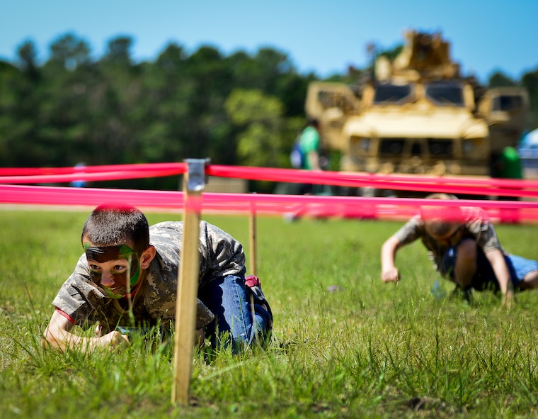 A little deployer low-crawls through a maze of red tape during Operation Hero April 12 at Eglin Air Force Base, Fla.  Nearly 400 adults and children participated in the program this year, which served as a way to help children understand the military and the deployment process their parents have or could face.  The kids went through a deployment line to get their uniforms, dog tags and shots before they were briefed by their commander and shipped off to a deployed location.  There, they encountered military demonstrations, equipment and obstacle courses.  (U.S. Air Force photo/Samuel King Jr.)