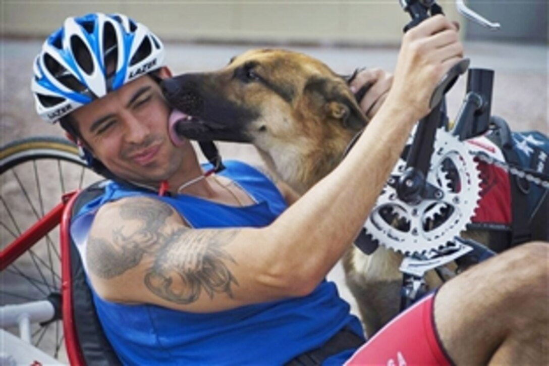 Air Force wounded warrior August O’Neill interacts with his service dog, Kai, during the cycling portion of the Air Force Warrior Games Trials on Nellis Air Force Base, Nev., April 9, 2014. O’Neill competed in the 6-mile men’s hand cycle heat with four others. Competitive ill, injured and wounded airmen and soldiers raced in seven heats stretching six to 18 miles on varying bike frames.