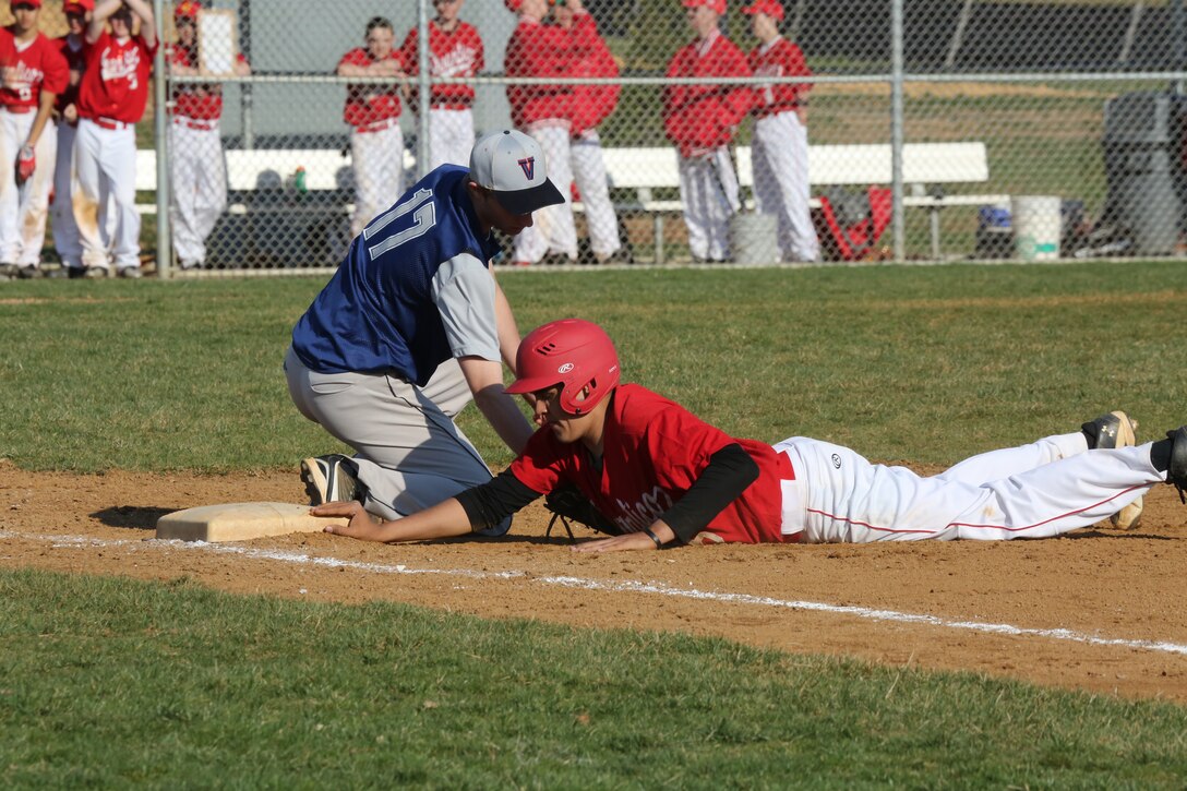 Anthony, a senior for the Quantico Middle/High School Warrior Baseball Team, dives toward first base during a pick-off attempt by the pitcher for the Holy Family Academy Vendeens from Manassas, Va., in a baseball game at George Hellwig Memorial Park in Manassas on April 9, 2014. The Vendeens trailed the Warrior into the last inning, but after three walks and two base hits, came back to win the game 11-10.
