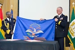 Maj. Gen. David Sprynczynatyk, North Dakota adjutant general, right, presents a North Dakota flag to Vice Adm. Mathew Quashie, the Ghanaian Armed Forces chief of the Defence Staff, during an anniversary celebration April 11, 2014 at the Memorial Hall of the State Capitol Building in Bismarck.