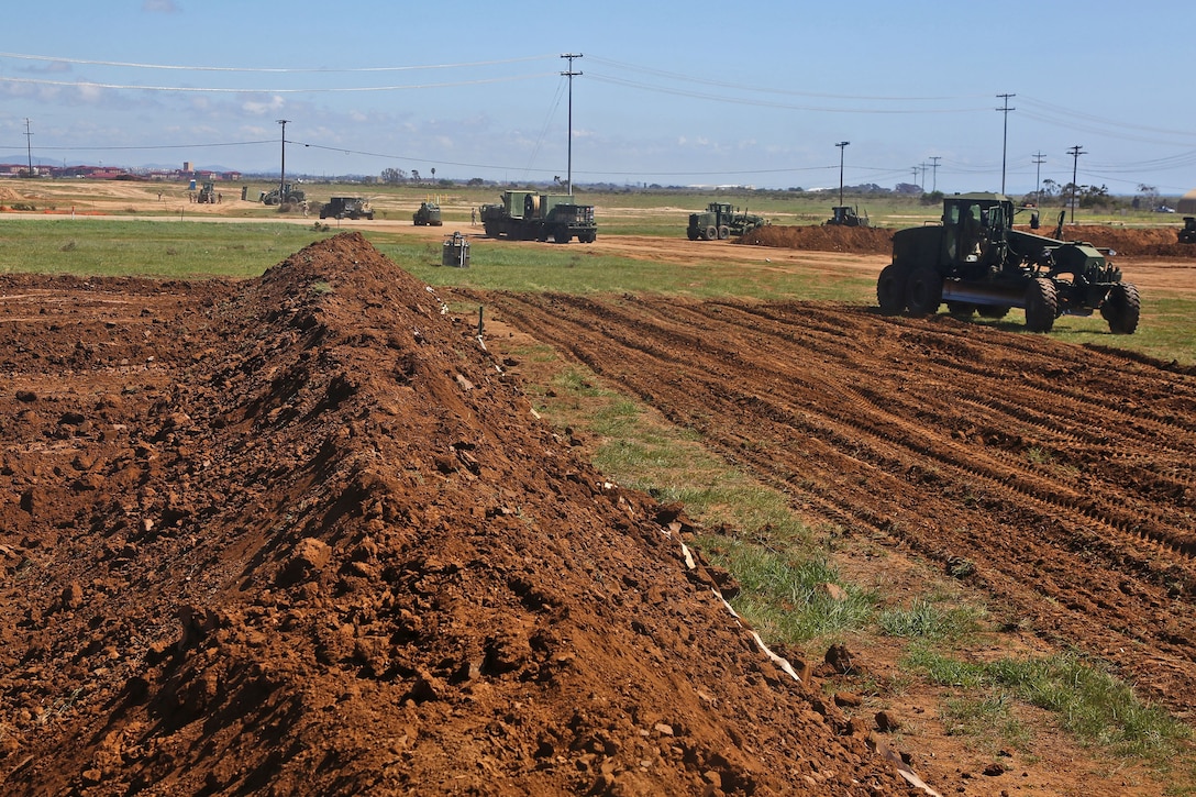 Heavy equipment operators with Bulk Fuel Company, 7th Engineer Support Battalion, 1st Marine Logistics Group, build earth-berms in the early stages of constructing an Amphibious Assault Fuel System, Camp Pendleton, Calif., April 2, 2014. The AAFS allows for the receiving, storage, and distribution of 1.3-million gallons of fuel. The system consists of a vast layout of 33 fuel bladders, each holding 20,000 to 50,000 gallons of fuel, placed inside six-foot tall earth berms, as a safety measure, to contain any spillage should a bladder rupture. 