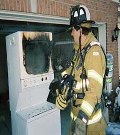 A firefighter looks at a burnt-out dryer. According to the Marine Corps Base Safety Division, more than 15,000 annual fires are caused by dryers. 