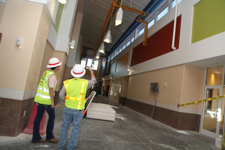 Dennis Campbell, Corps quality assurance representative, and Tracy Robillard, public affairs specialist, discuss how brightly colored pipes show children how hot and cold water circulates through the new Murray Elementary School. The pipes serve as a functional teaching aid for children to learn about environmentally sustainable building practices. 