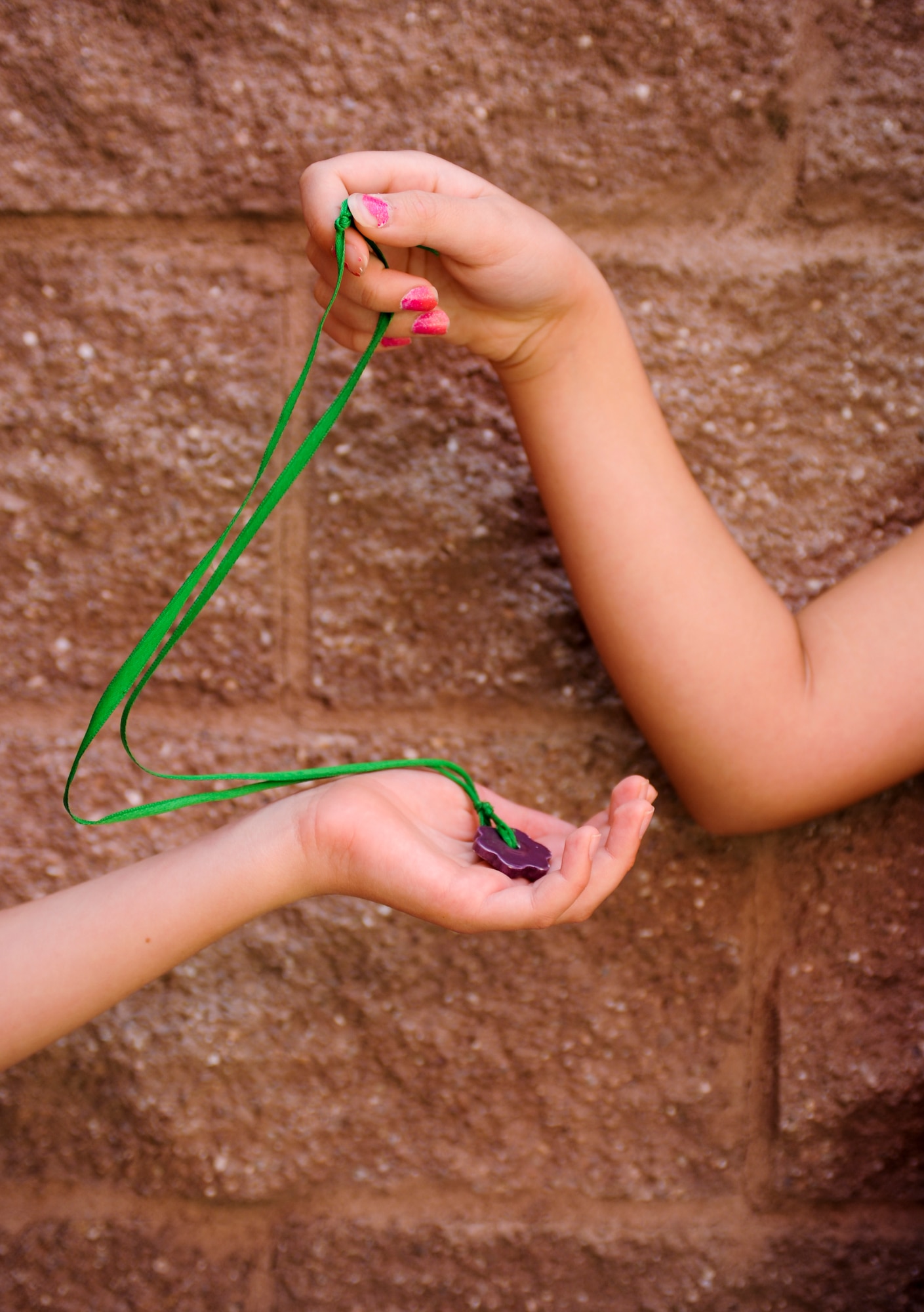 Jack Vuturo, third-grader, receives a “Be Kind” program coin necklace from Milee Kamell, a fourth-grader, at Soleng Tom Elementary School in Tucson, Ariz., April 10, 2014. “Be Kind” coin necklaces are given to students who perform an act of kindness throughout the week. (U.S. Air Force photo by Senior Airman Sivan Veazie/Released)