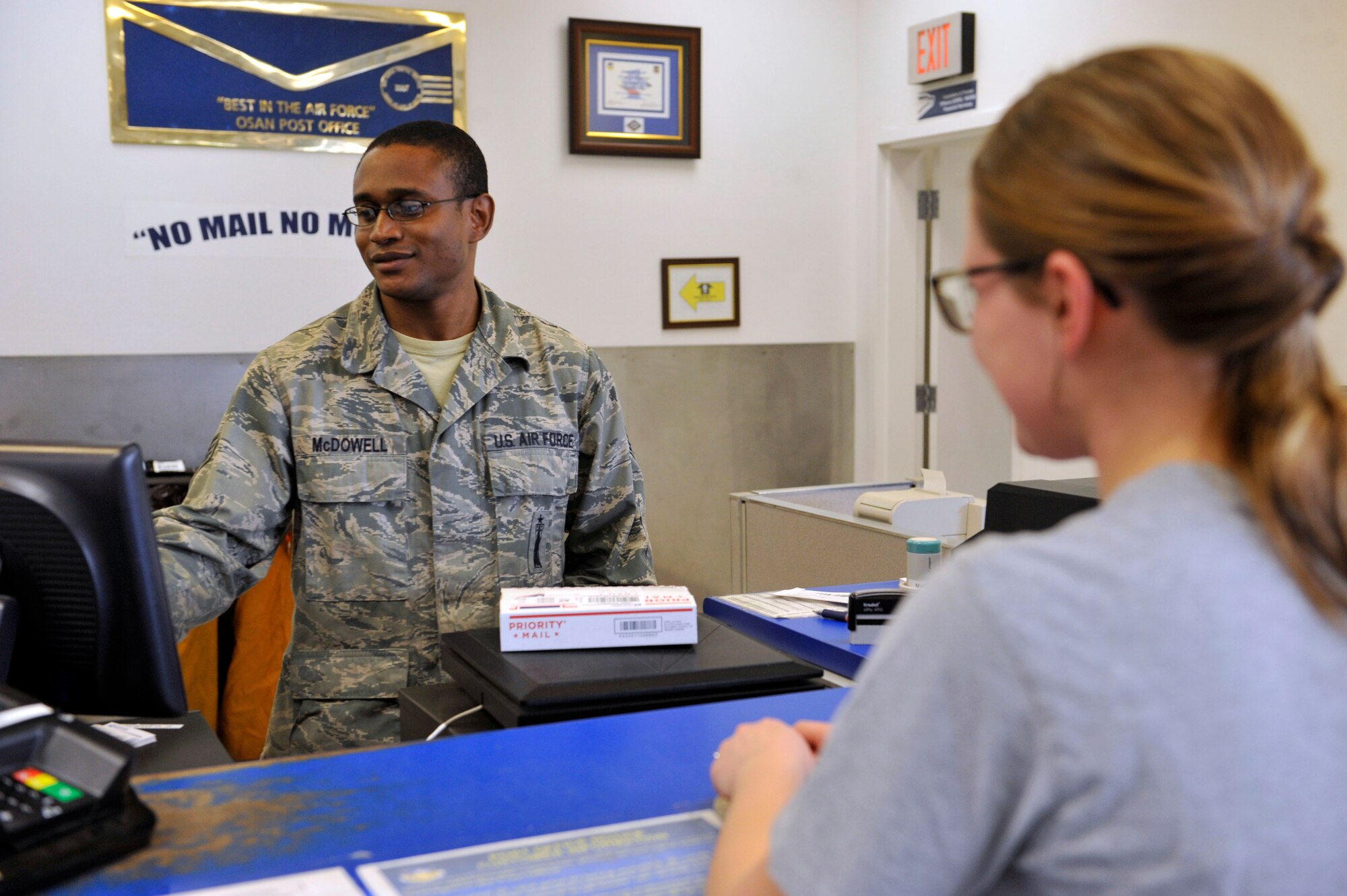 Staff Sgt. Timothy McDowell, a 51st Communication Squadron postal effects custodian, gets the price and weight of a flat rate box for Senior Airman Alyssa McConnell, 51st Aircraft Maintenance Squadron weapons journeyman April 10, 2014 at the post office at Osan Air Base, Republic of Korea. The postal service center is responsible for processing all personal mail and ensuring delivery of all parcels and letter class mail. (U.S. Air Force photo by Senior Airman David Owsianka)