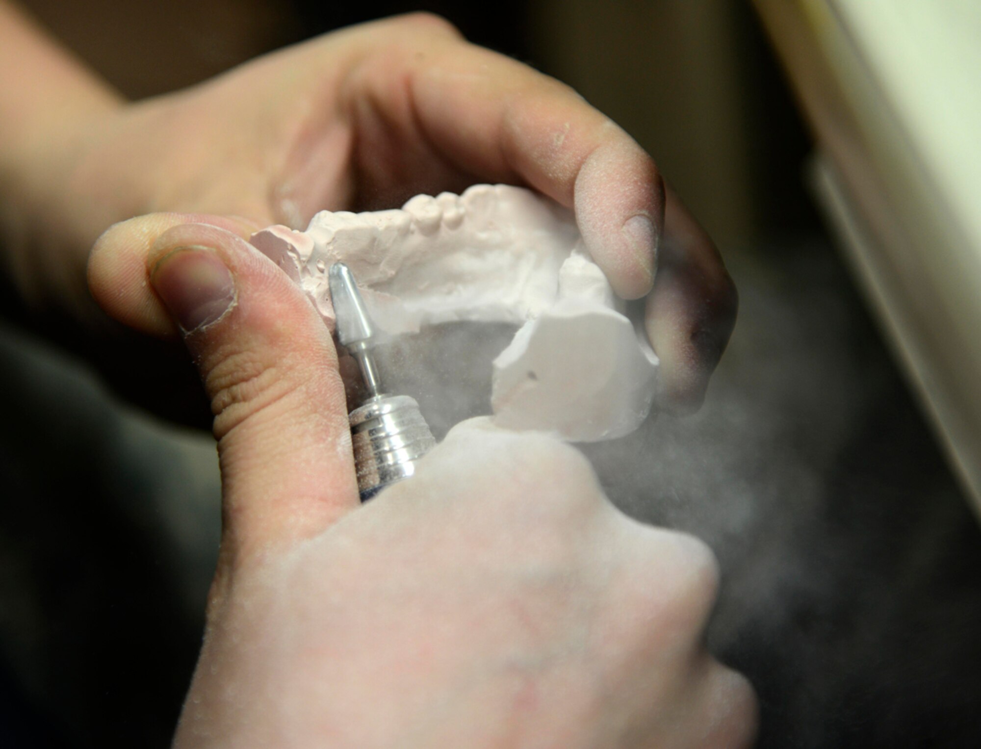 Senior Airman Joseph Dumancas, 673d Dental Squadron dental lab technician, trims a dental cast in preparation for the fabrication of a removal partial denture at Joint Base Elmendorf-Richardson, Alaska, April 8, 2014. An RPD usually consists of replacement teeth attached to pink or gum-colored plastic bases. (U.S. Air Force photo/Staff Sgt. Sheila deVera)