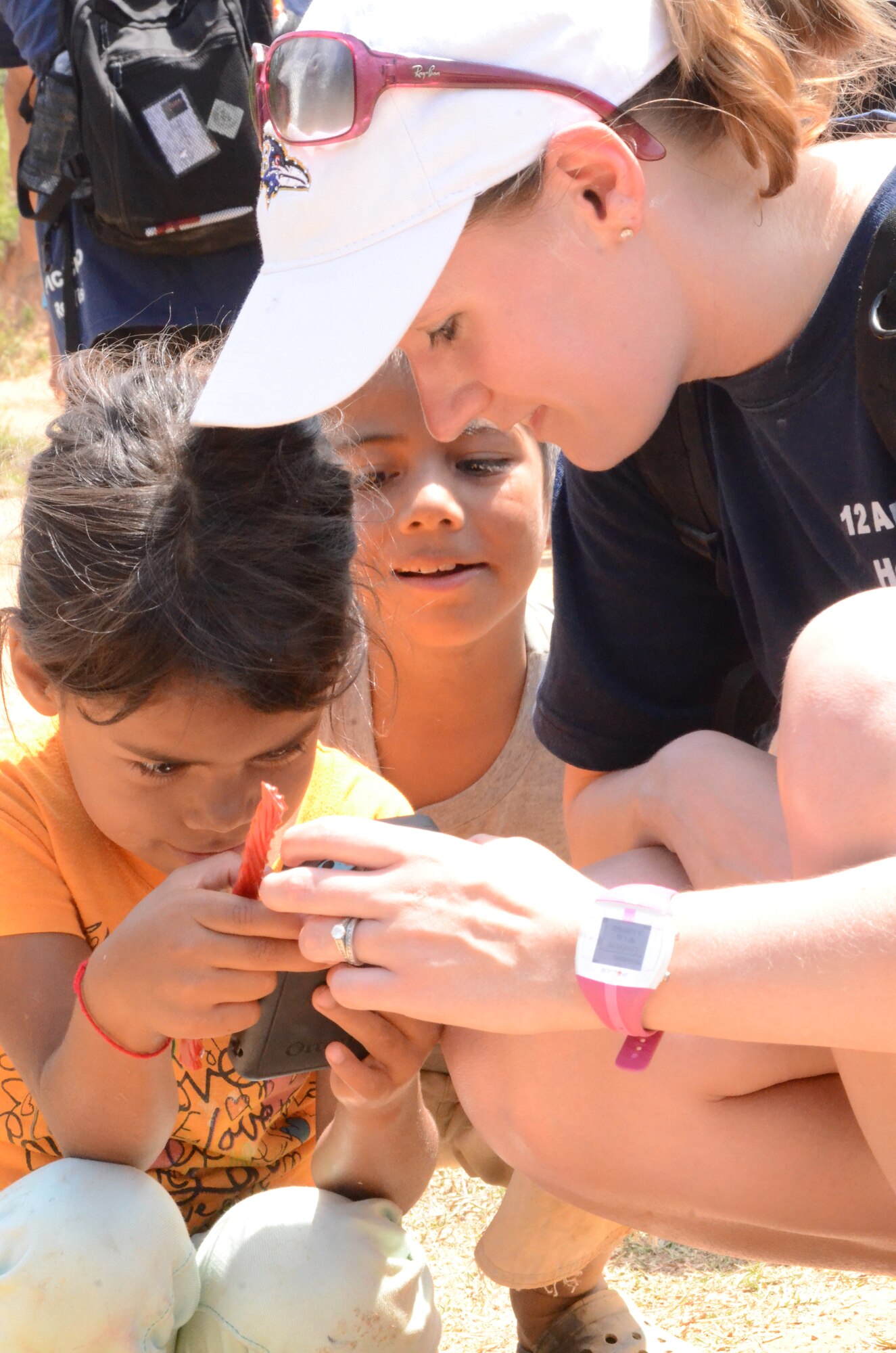A Joint Task Force service member shares some licorice and shows pictures to a Honduran girl.  More than 130 members of Joint Task Force-Bravo completed a 6.2 mile round trip hike to deliver more than 3,000 pounds of food and supplies to families in need in the mountain village, April 12, 2014. During the more than three mile trek up the mountain, Task Force members made an elevation gain of 1,600 feet while carrying more than 25 pounds of supplies each. The food and supplies were all purchased with donations made by the members of Joint Task Force-Bravo. (Photo by U. S. Air Force Technical Sgt. Breihan Fetz)