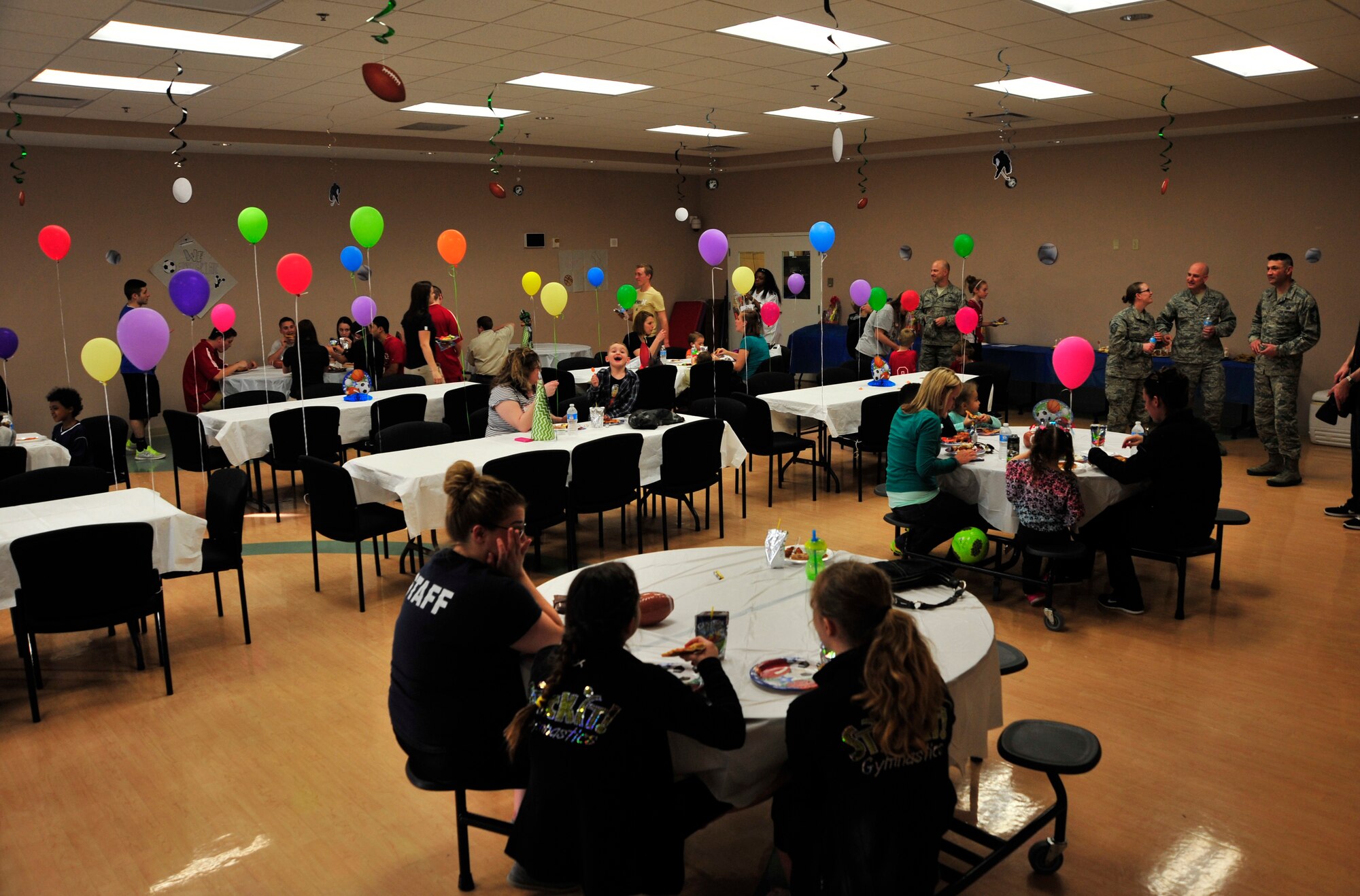 Spouses and family members of deployed Team Dover Airmen as well as volunteers for the event socialize during a deployed spouses dinner at the Youth Center April 10, 2014, at Dover Air Force Base, Del. The 436th Medical Group hosted the sports themed event that included dinner, crafts, a bounce house and other activities. (U.S. Air Force photo/Staff Sgt. Elizabeth Morris)