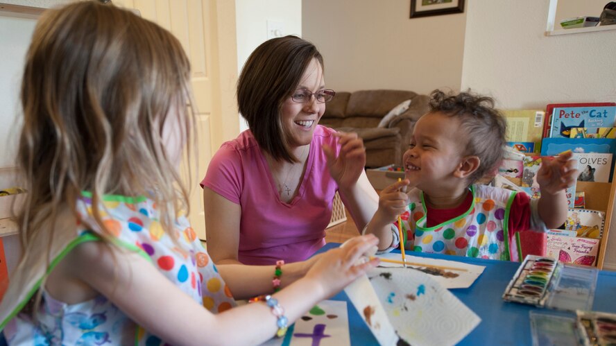 Tiffany Heppler, family child care provider, laughs with Ashley, left, her daughter, and Etienne during crafts time, April 11, 2014,in base housing on Dover Air Force Base, Del. Heppler is able to care for her own children while also taking care of other kids. (U.S. Air Force photo/Senior Airman Jared Duhon) 