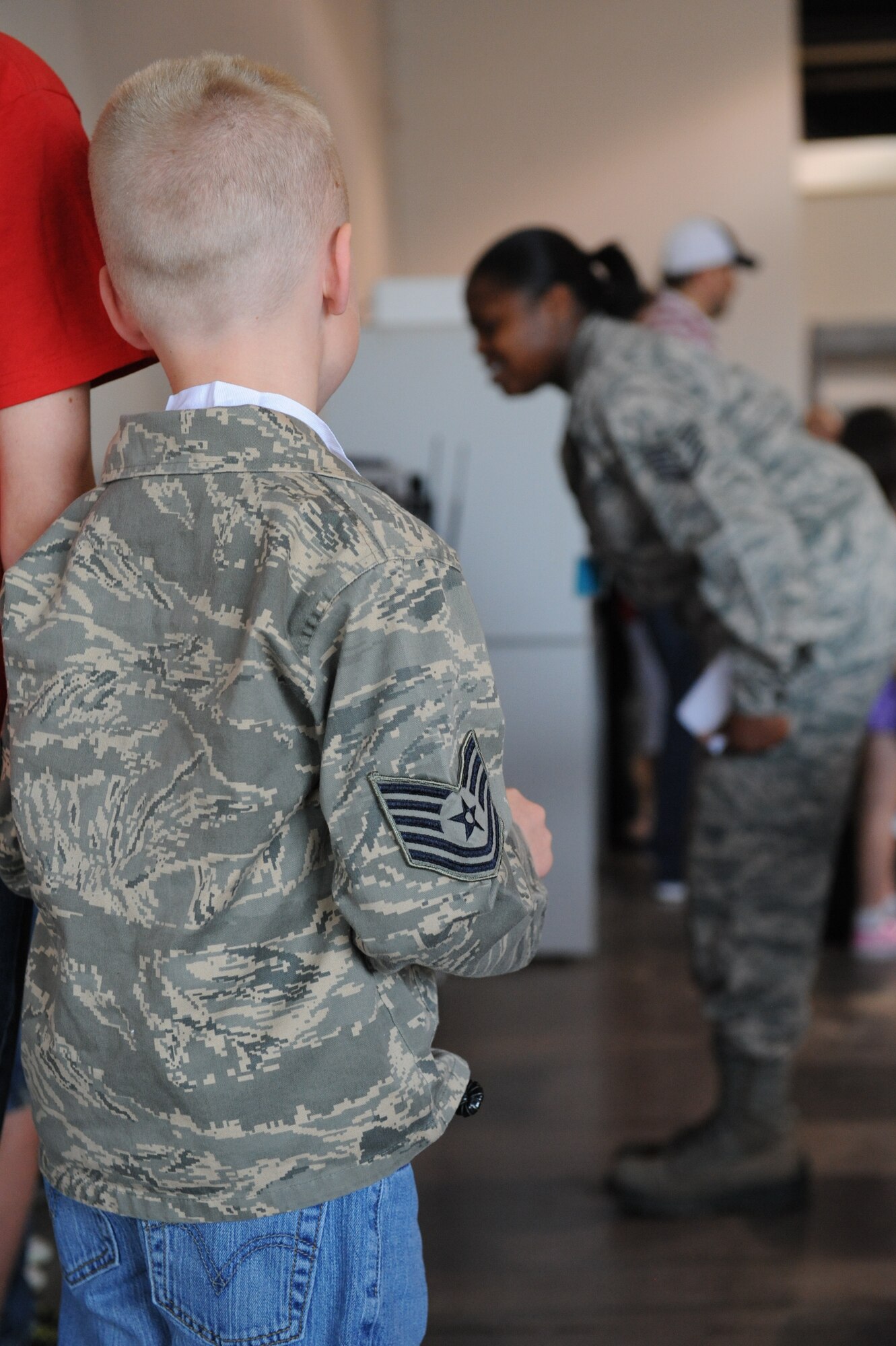 An Operation Spirit “deployer” watches as Tech Sgt. Shonta Simes, 509th Force Support Squadron dining facility manager and event volunteer, instructs her “deployers” on how to stand at attention and perform different facing movements at Whiteman Air Force Base, Mo., April 12, 2014. Operation Spirit is an event put on in support of the “Month of the Military Child," recognizing the contributions children make as their parents serve our nation. (U.S. Air Force photo/Airman 1st Class Joel Pfiester/Released)