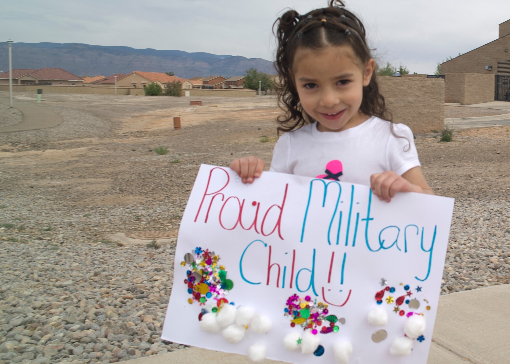 A dependent of a Team Holloman member shows off her custom poster as she participates in a parade at Holloman Air Force Base N.M., April 11.  April is recognized the Month of the Military Child, created by Secretary of Defense Caspar W. Weinberger in 1986.  This month highlights the contribution that military children make as their parent or parents serve our nation.  It is during April of each year that all branches of services provide special days and events to honor military children. (U.S. Air Force photo by Staff Sgt. Warren Spearman / Released) 