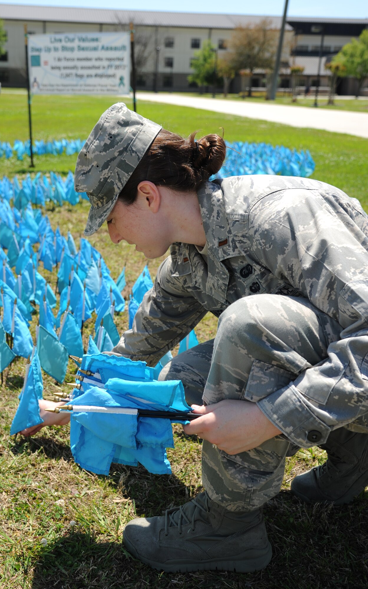 Second Lt. Tawny Gardner, 81st Force Support Squadron, places teal-colored flags in the ground in the shape of a ribbon for Sexual Assault Awareness Month April 11, 2014 at the triangle parade grounds, Keesler Air Force Base, Miss.  Each flag represents one Air Force member who reported being sexually assaulted in fiscal year 2013.  There are 1,047 flags displayed.  (U.S. Air Force photo by Kemberly Groue)
