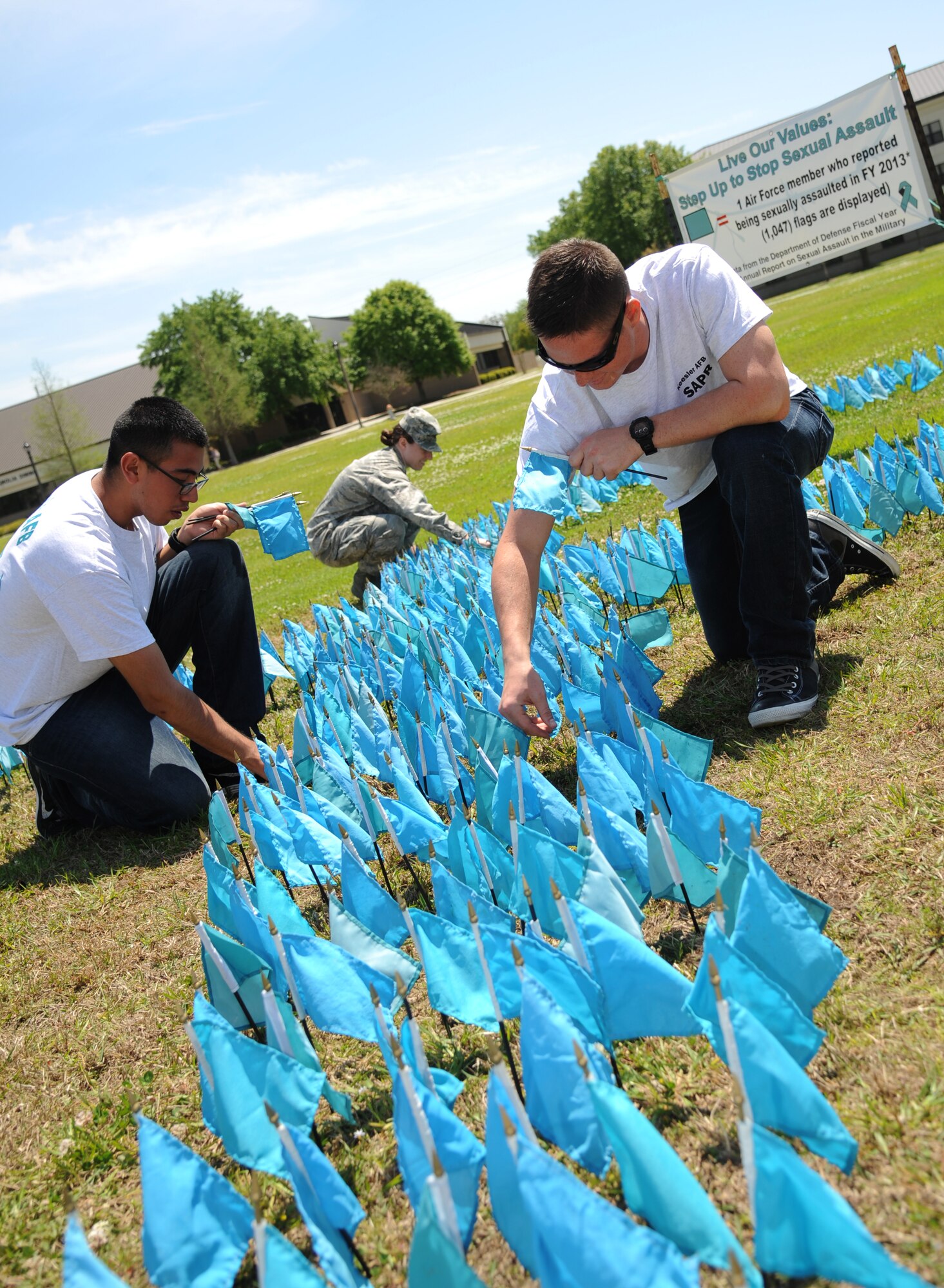 Airmen 1st Class Antonio Ruiz, and Adam Duplain, 336th Training Squadron and teal rope members, and 2nd Lt. Tawny Gardner, (center), 81st Force Support Squadron, places teal-colored flags in the ground in the shape of a ribbon for Sexual Assault Awareness Month April 11, 2014 at the triangle parade grounds, Keesler Air Force Base, Miss.  Each flag represents one Air Force member who reported being sexually assaulted in fiscal year 2013.  There are 1,047 flags displayed.  (U.S. Air Force photo by Kemberly Groue)
