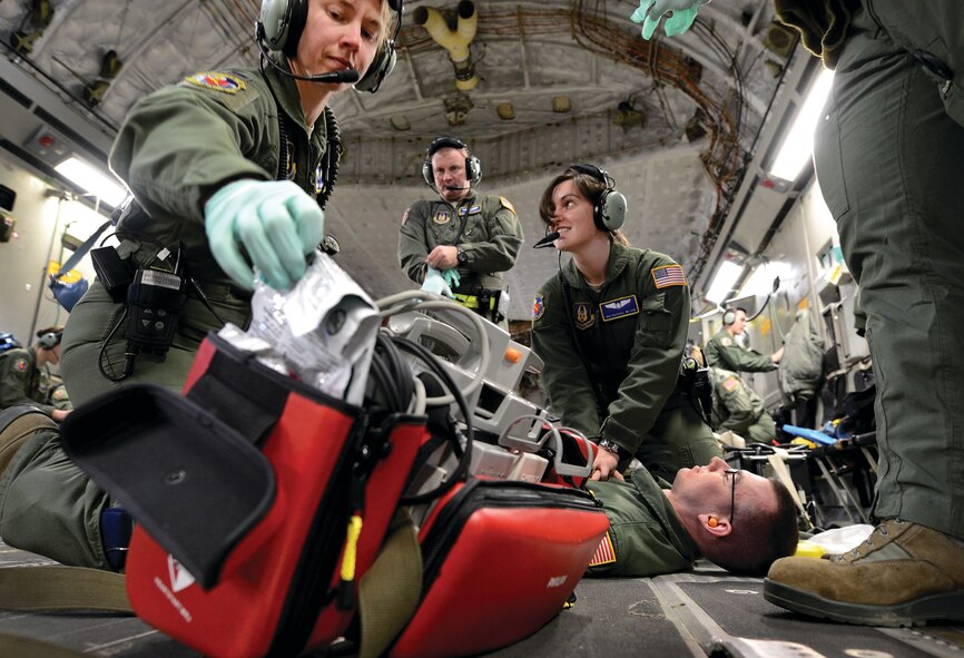 WRIGHT-PATTERSON AIR FORCE BASE, Ohio - Senior Airman Sean Seminsky portrays a patient with an in-flight cardiac emergency as Senior Airman Rachael Wilson, right, performs chest compressions. First Lieutenant Shauna Piotrowski, left, prepares to attach an AED and Master Sgt. Fredrick Hageman III, background, puts on personal protective equipment. All are assigned to the 445th Aeromedical Evacuation Squadron. (U.S. Air Force photo/Tech. Sgt. Frank Oliver)