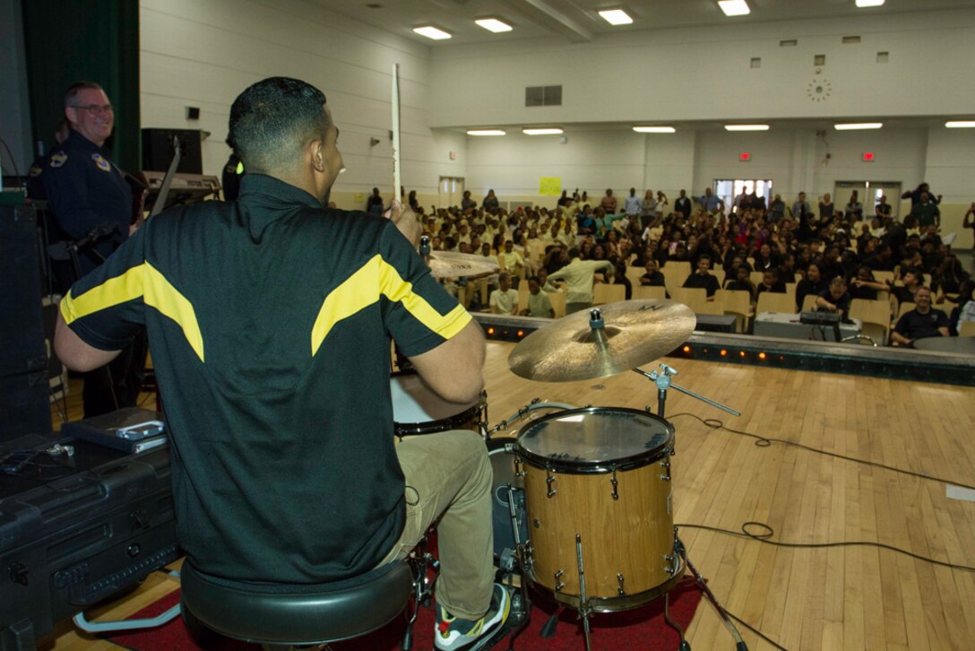 Charles Hart Middle School health and physical education teacher Eian Jackson lays down some beats on stage with the U.S. Air Force Band’s Max Impact during a performance at the school March 26, 2014. During a question and answer session one of the students revealed that their teacher played the drums which prompted Master Sgt. Ryan Carson, one of the band’s vocalists, to invite Jackson on stage to show-off his talent. (U.S. Navy photo by Lt. Cmdr. Jim Remington)