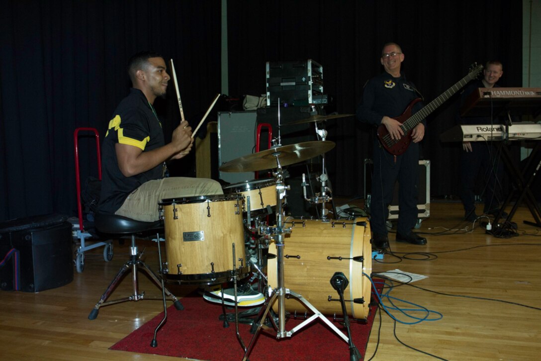 Charles Hart Middle School health and physical education teacher Eian Jackson lays down some beats on stage with the U.S. Air Force Band’s Max Impact during a performance at the school March 26, 2014. During a question and answer session one of the students revealed that their teacher played the drums which prompted Master Sgt. Ryan Carson, one of the band’s vocalists, to invite Jackson on stage to show-off his talent. (U.S. Navy photo by Lt. Cmdr. Jim Remington)