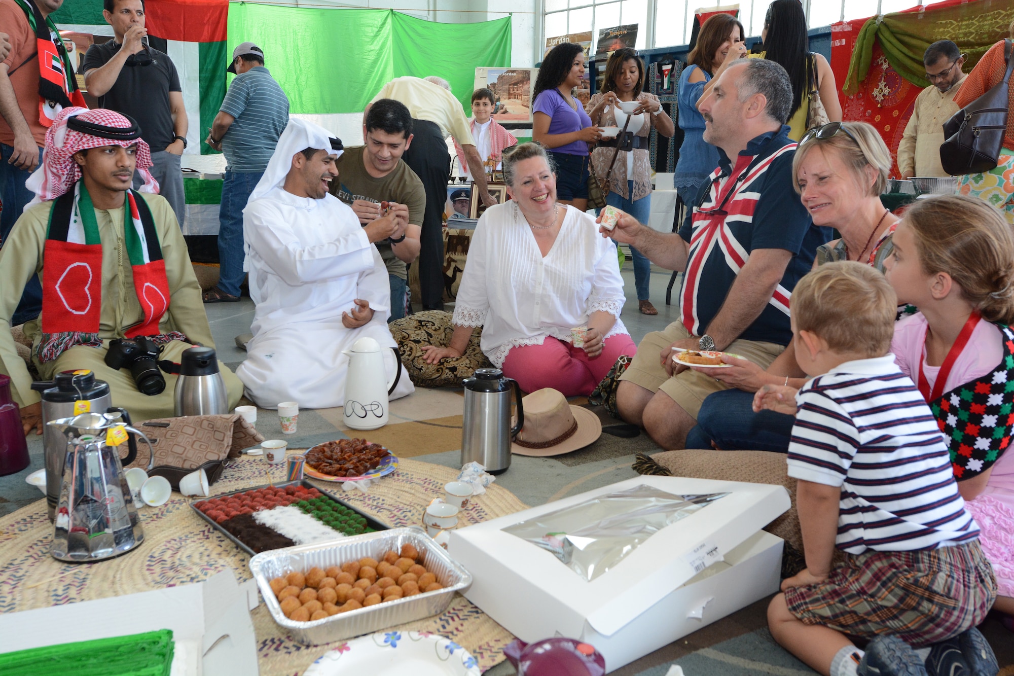 Group Capt. Clive Blount, right, and his family share tea with representatives of the United Arab Emirates at their booth during the AWC International Culture Festival, held at Maxwell Air Force Base, April 12, 2014. The UAE students and their friends and families replicated their traditional customs for their American and international peers in order to share their cultural heritage during the festival. (U.S. Air Force photo by Staff Sgt. Gregory Brook)