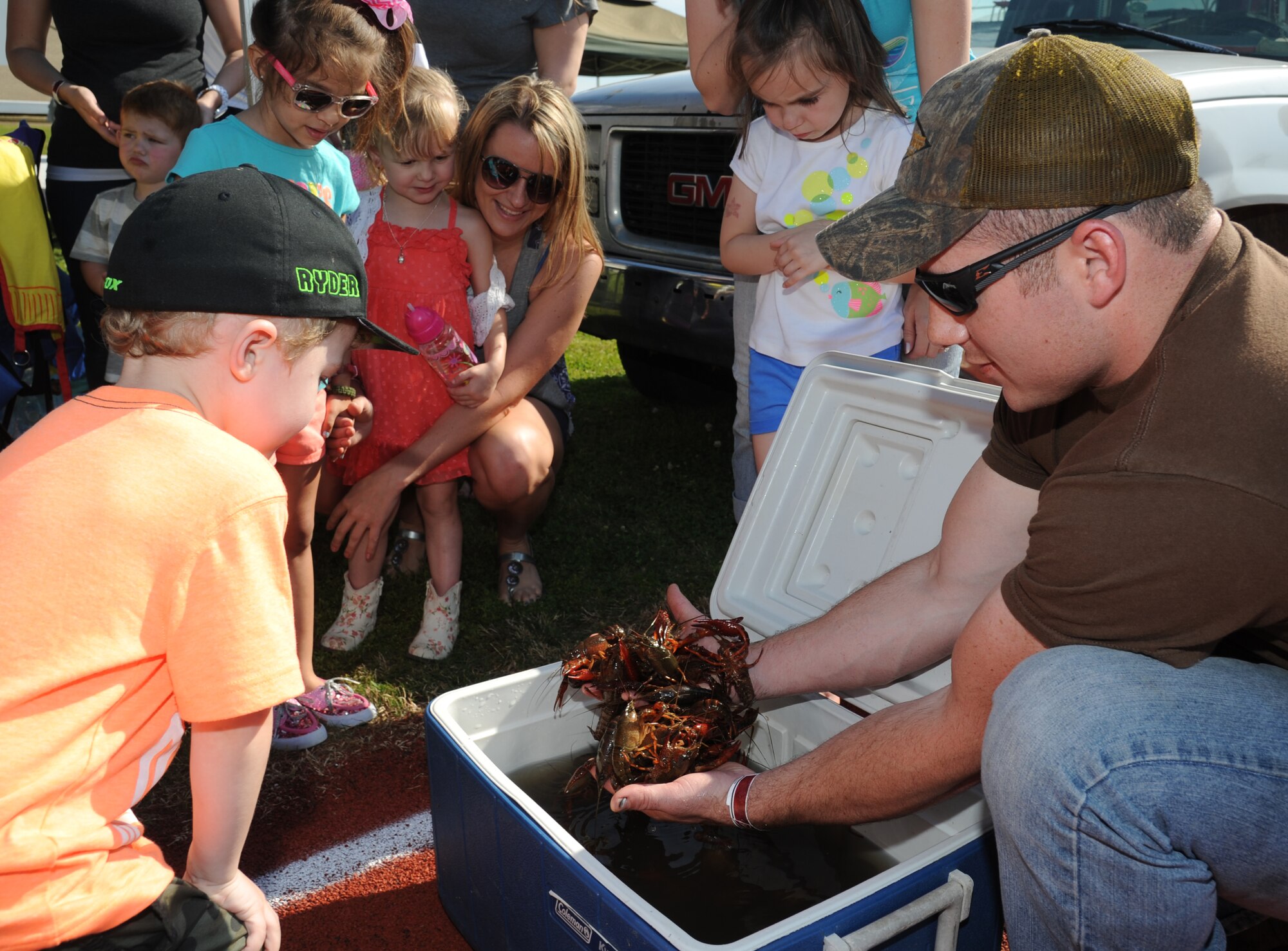 Senior Airman Kevin Rozas, 81st Security Forces Squadron, shows a handful of live crawfish from a cooler to Keesler children during the 2nd Annual Bay Breeze Crawfish Cook-Off April 11, 2014, at the Bay Breeze Event Center, Keesler Air Force Base, Miss.  The trophy was taken by the “Cajun Snappa” team, who will receive a free entry into the 22nd Annual Mississippi Coast Coliseum Crawfish Festival Cook-Off.  (U.S. Air Force photo by Kemberly Groue)