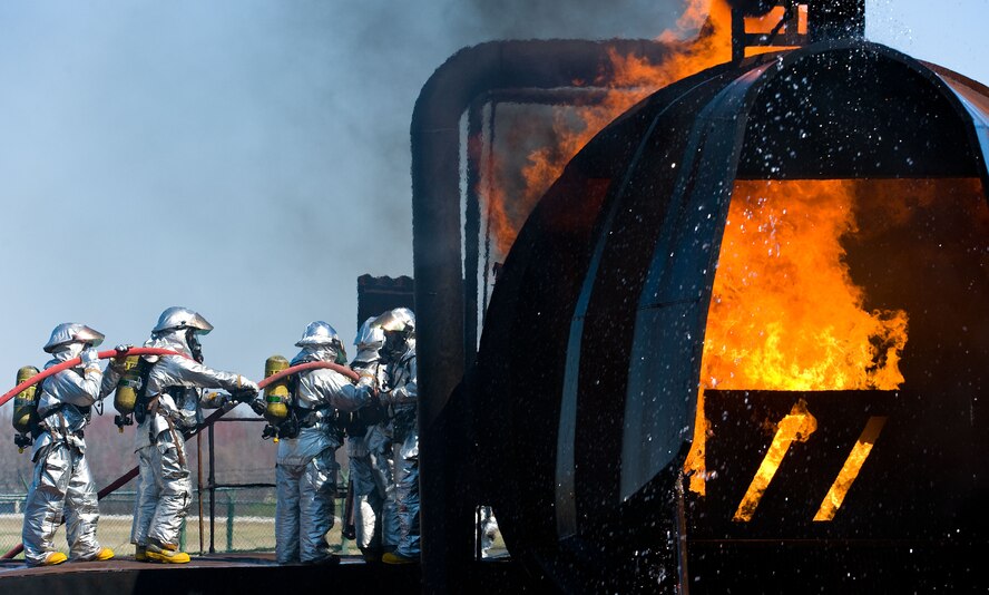 A 436th Civil Engineer Squadron Fire Department four-person fire attack crew enters the aircraft fire trainer April 10, 2014, at Dover Air Force Base, Del. The fire attack crew practiced engaging and extinguishing flames originating from the flight deck and cargo compartment areas. (U.S. Air Force photo/Roland Balik)