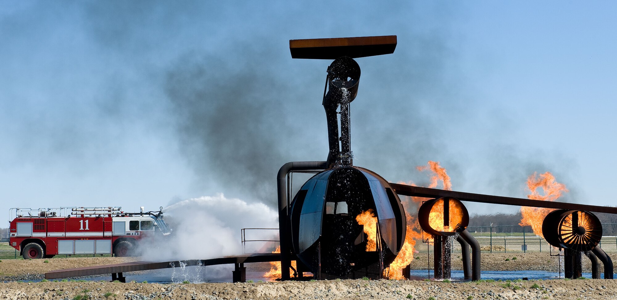 Crash 11, a Striker T-1500 firetruck from the 436th Civil Engineer Squadron Fire Department aims a stream of water at flames engulfing the fuselage and engines of the aircraft fire trainer April 10, 2014, at Dover Air Force Base, Del. The T-1500 is capable of dispensing 1,250 gallons of water per minute. (U.S. Air Force photo/Roland Balik)