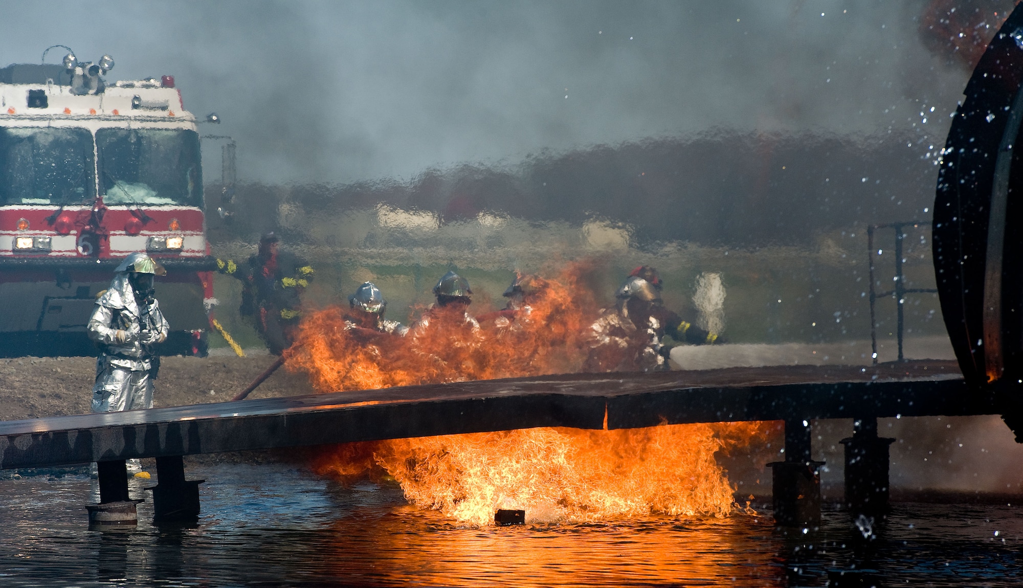 Two fire attack crews from the 436th Civil Engineer Squadron Fire Department aim streams of water on the left wing of the aircraft fire trainer April 10, 2014, at Dover Air Force Base, Del. Fire attack crews wear aircraft rescue and firefighting proximity gear for protection when battling aircraft fires. (U.S. Air Force photo/Roland Balik)