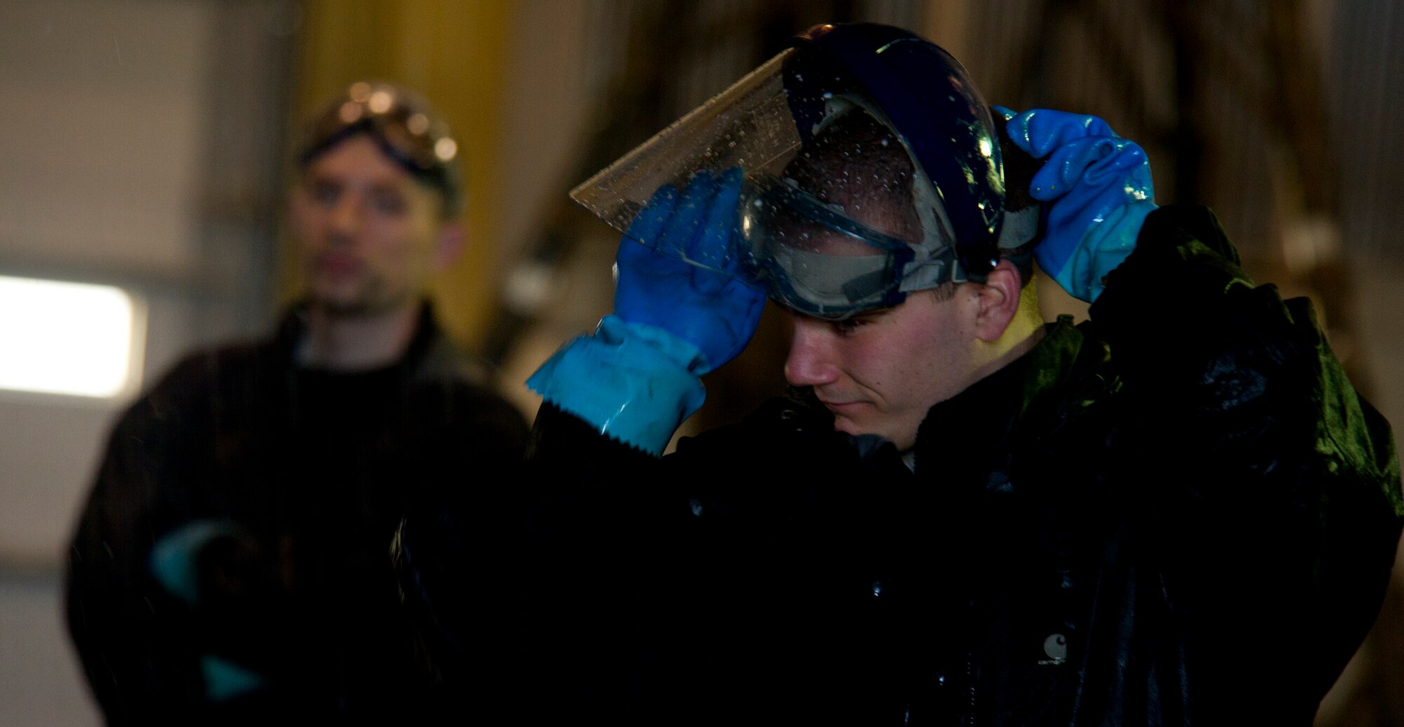 Airman 1st Class Daniel Starr, 5th Aircraft Maintenance Squadron crew chief, pulls his face shield down while a B-52H Stratofortress is washed on Minot Air Force Base, N.D., March 10, 2014. The 5th AMS consists of two aircraft maintenance unit specialist sections, the 23rd and 69th AMU with a total of 237 maintenance professionals spanning across six Air Force specialties including Communications/Navigation, Instruments/Flight Controls, Electronic Counter Measures, Jet Engine Mechanics, Hydraulics and Electrical/Environmental systems. (U.S. Air Force photo/Senior Airman Brittany Y. Auld)