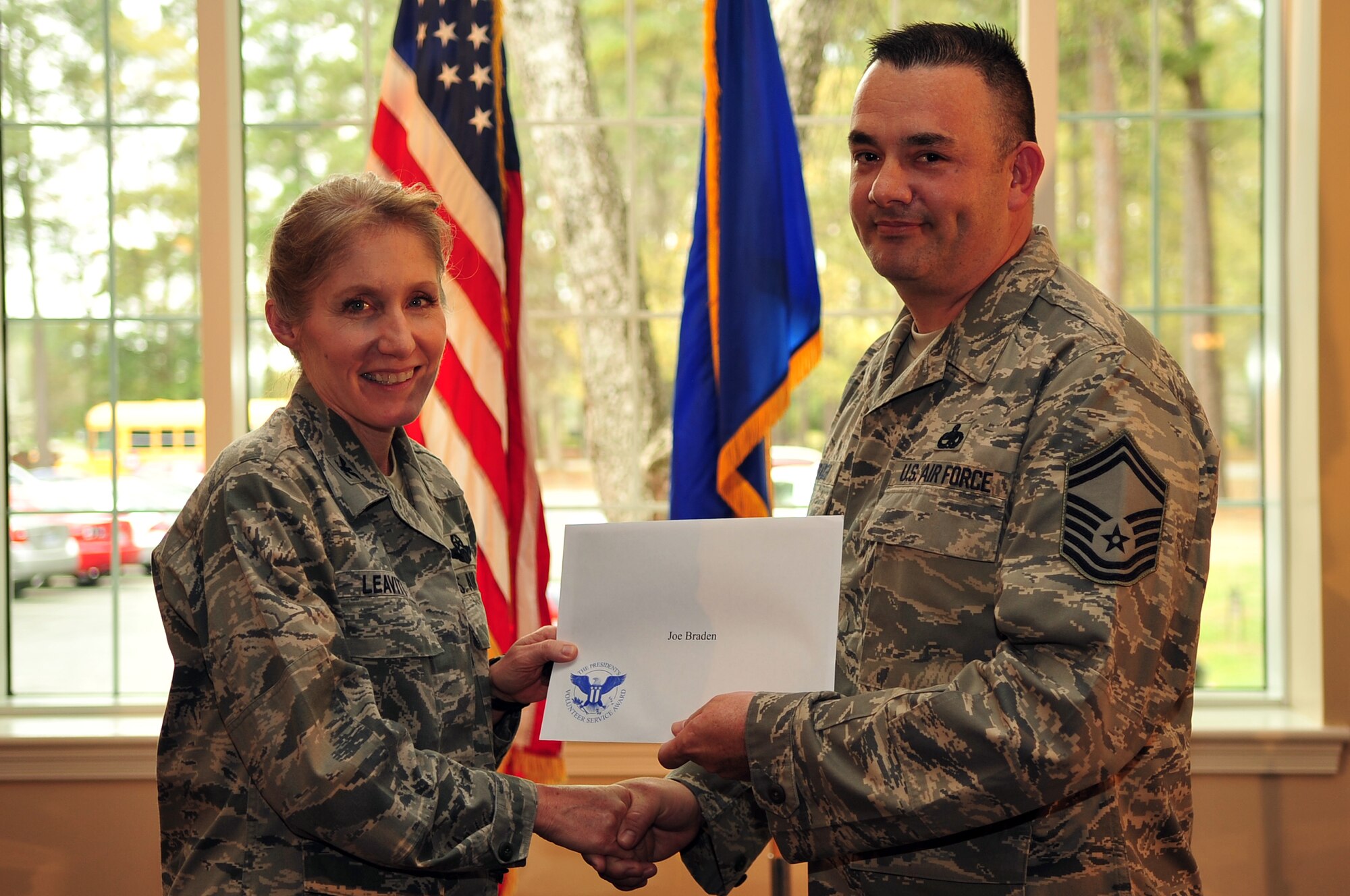 U.S. Air Force Col. Jeannie Leavitt, 4th Fighter Wing commander, left, presents Senior Master Sgt. Joseph Braden, 4th Components Maintenance Squadron assistance maintenance superintendent with the Bronze Presidential Service Award, April 9, 2014, at Seymour Johnson Air Force Base, N.C. Braden was also presented the Military Outstanding Volunteer Service Medal for his volunteer efforts from 2007 through 2013. (U.S. Air Force photo/Airman 1st Class Shawna L. Keyes)