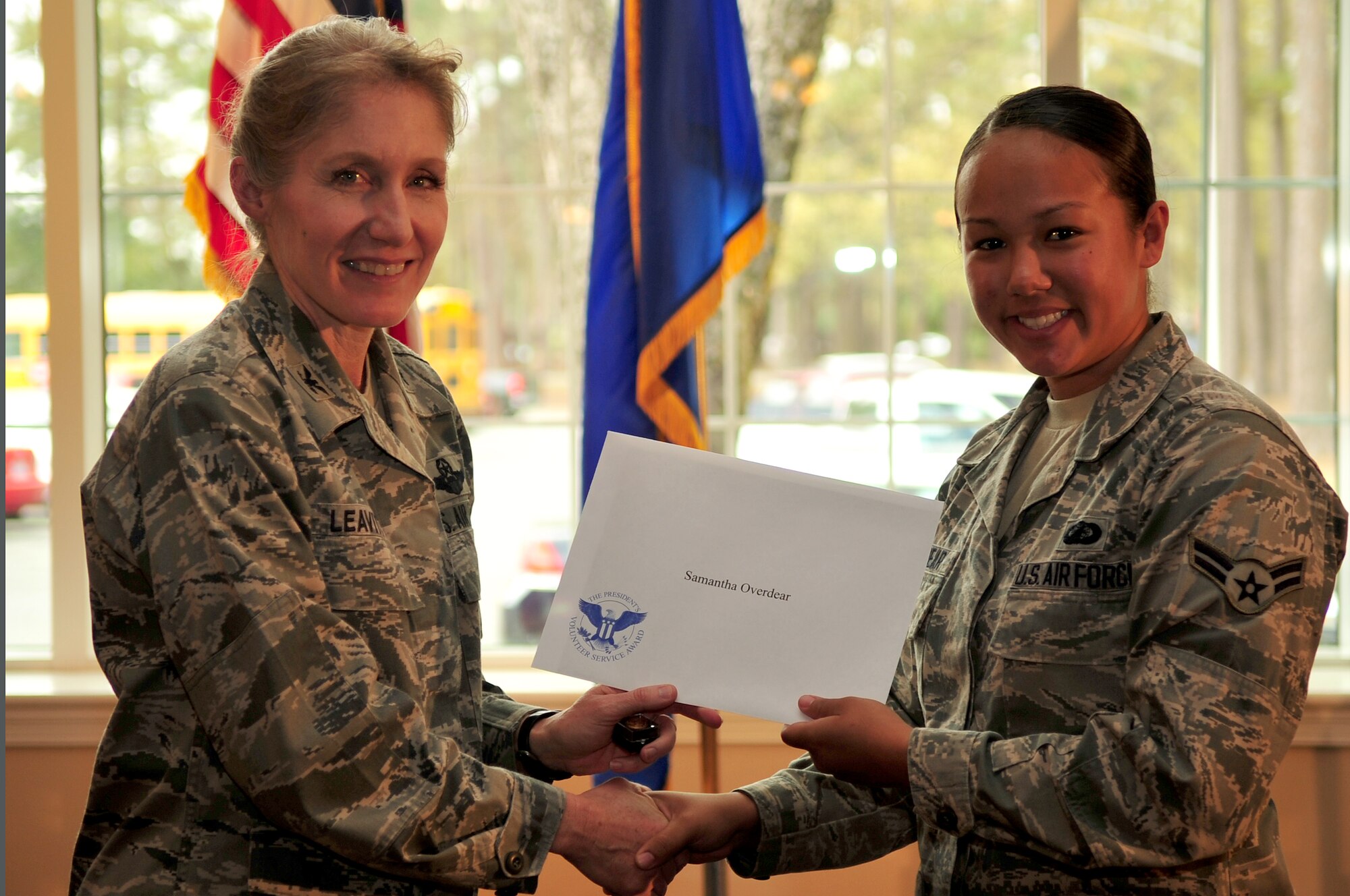 U.S. Air Force Col. Jeannie Leavitt, 4th Fighter Wing commander, left, presents Airman 1st Class Samantha Overdear, 4th Contracting Squadron contract specialist with the Gold Presidential Service Award, April 9, 2014, at Seymour Johnson Air Force Base, N.C. This award was presented to Overdear for her services with Airmen Against Drunk Driving, where she volunteered more than 270 hours. (U.S. Air Force photo/Airman 1st Class Shawna L. Keyes)