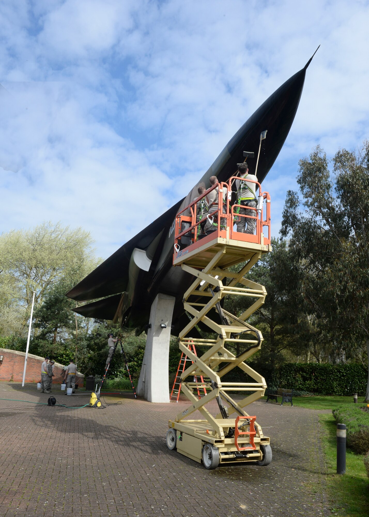 Airmen from the 48th Equipment Maintenance Squadron use a scissor lift and ladders to clean static displays on planes at the airpark on Royal Air Force Lakenheath, England, April 11, 2014. Airmen volunteered as part of a 48th Fighter Wing Historian duty intiative to maintain base static displays. (U.S. Air Force photo by Airman 1st Class Nigel Sandridge/Released)
