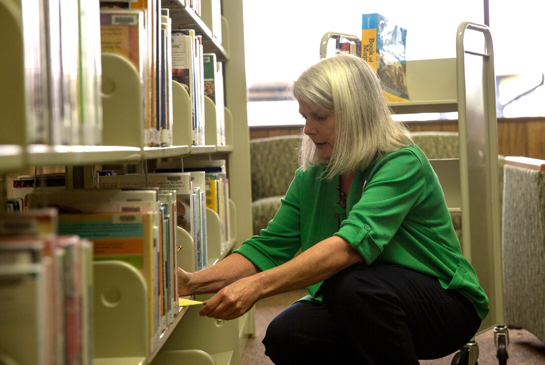 Patti Hall, a catalog librarian, looks over notes while shelving books at the Harriotte B. Smith library aboard Marine Corps Base Camp Lejeune, April 15. The library was closed for four months due to renovations and reopened April 1.  