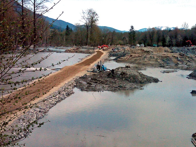 The U.S. Army Corps of Engineers, Seattle District, has nearly completed construction of the temporary berm within the SR530 slide area. Though the berm is complete in length, construction efforts have now shifted to raising the berm an additional foot ahead of predicted heavy rainfall. The additional height is expected to help reduce potential flooding risks, and the Corps is maintaining close coordination and communication with Snohomish County officials as recovery workers continue to search the area.  
