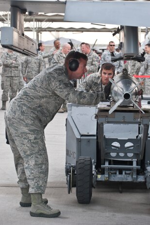 Staff Sgt. Daniel Armstrong, 57th Aircraft Maintenance Squadron, Tomahawk Aircraft Maintenance Unit load crew team chief, and Airman 1st Class Ryan Anderson, 57th AMXS Tomahawk AMU load crew member, load an MK-82 bomb onto and F-16 Fighting Falcon during a load crew competition on the flightline April 11, 2014, at Nellis Air Force Base, Nev. The Airmen are graded on a written test, dress and appearance, their composite tool kit and the ability to load weapons onto the aircraft. (U.S. Air Force photo by Senior Airman Matthew Lancaster)